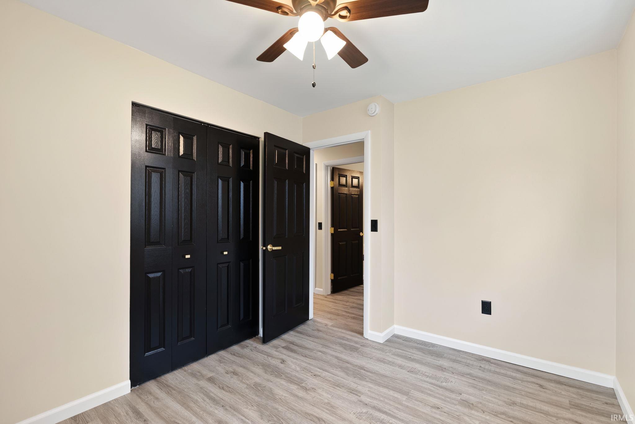 Unfurnished bedroom with light wood-type flooring, ceiling fan, and a closet