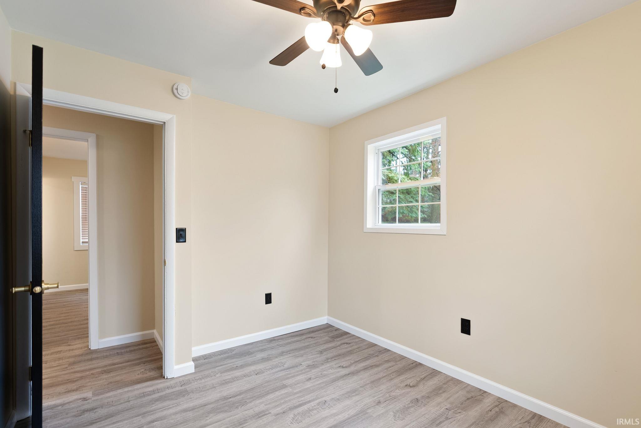 Empty room with ceiling fan and light wood-style floors