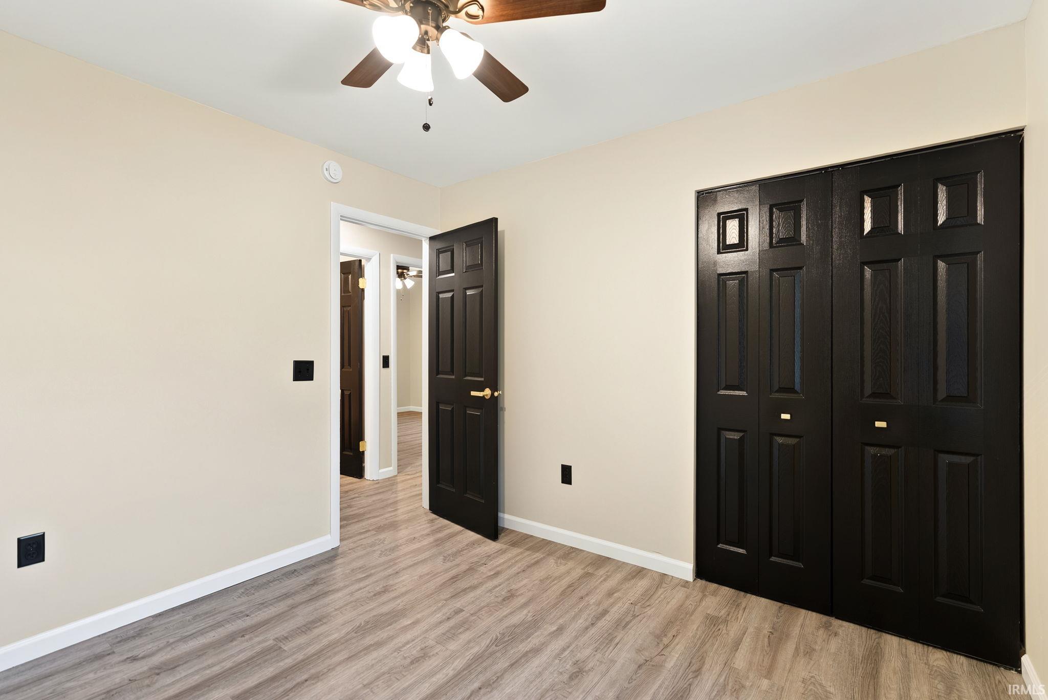 Unfurnished bedroom featuring light wood-style floors, a closet, and ceiling fan