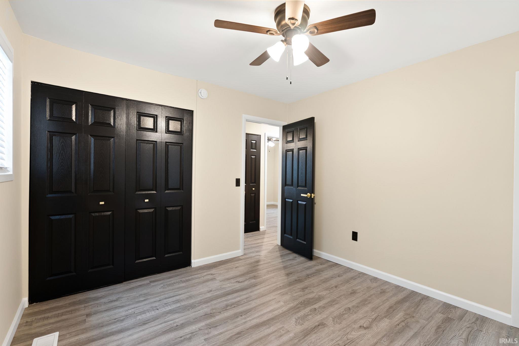 Unfurnished bedroom with light wood-style floors, a ceiling fan, and a closet