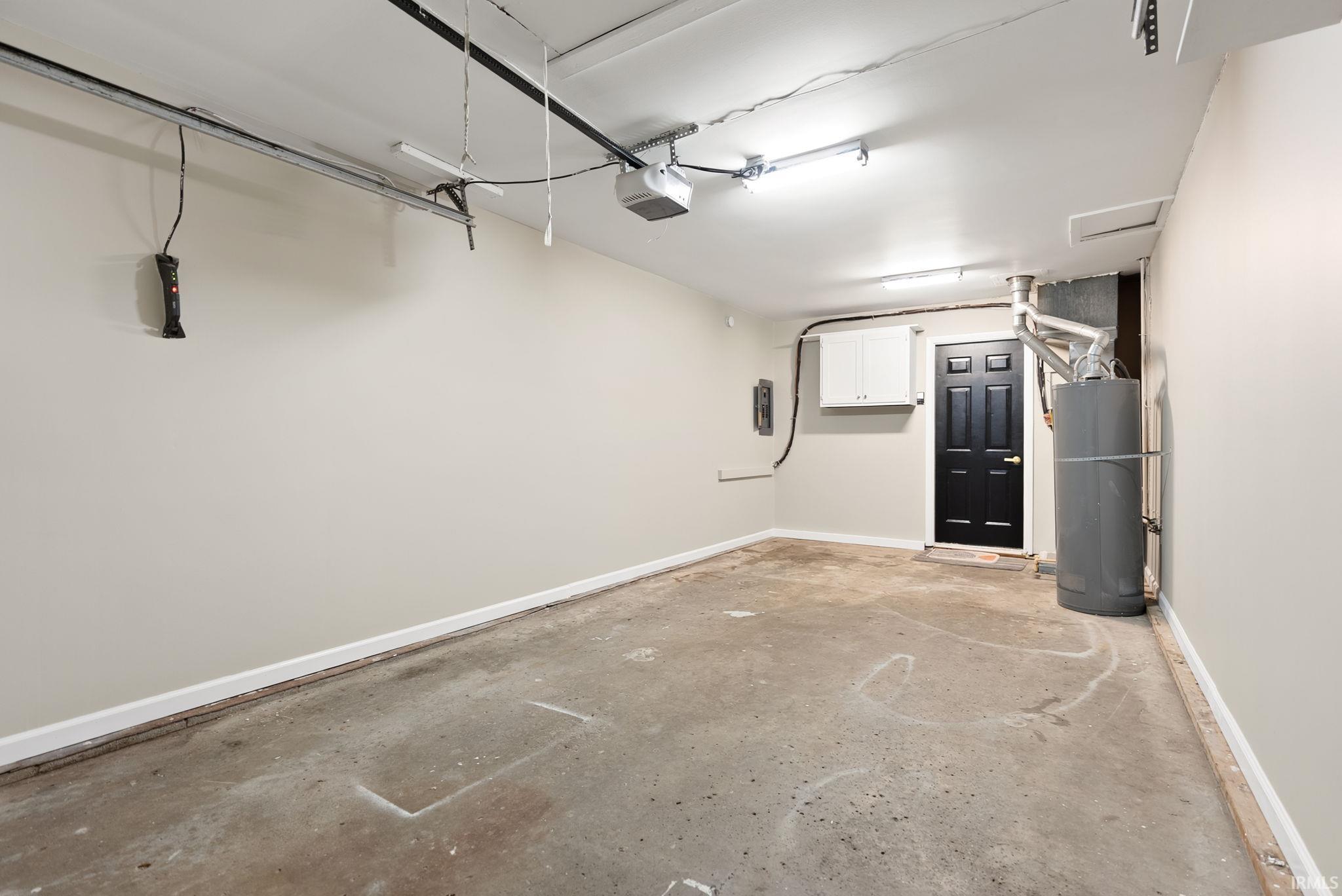 Garage featuring baseboards and water heater