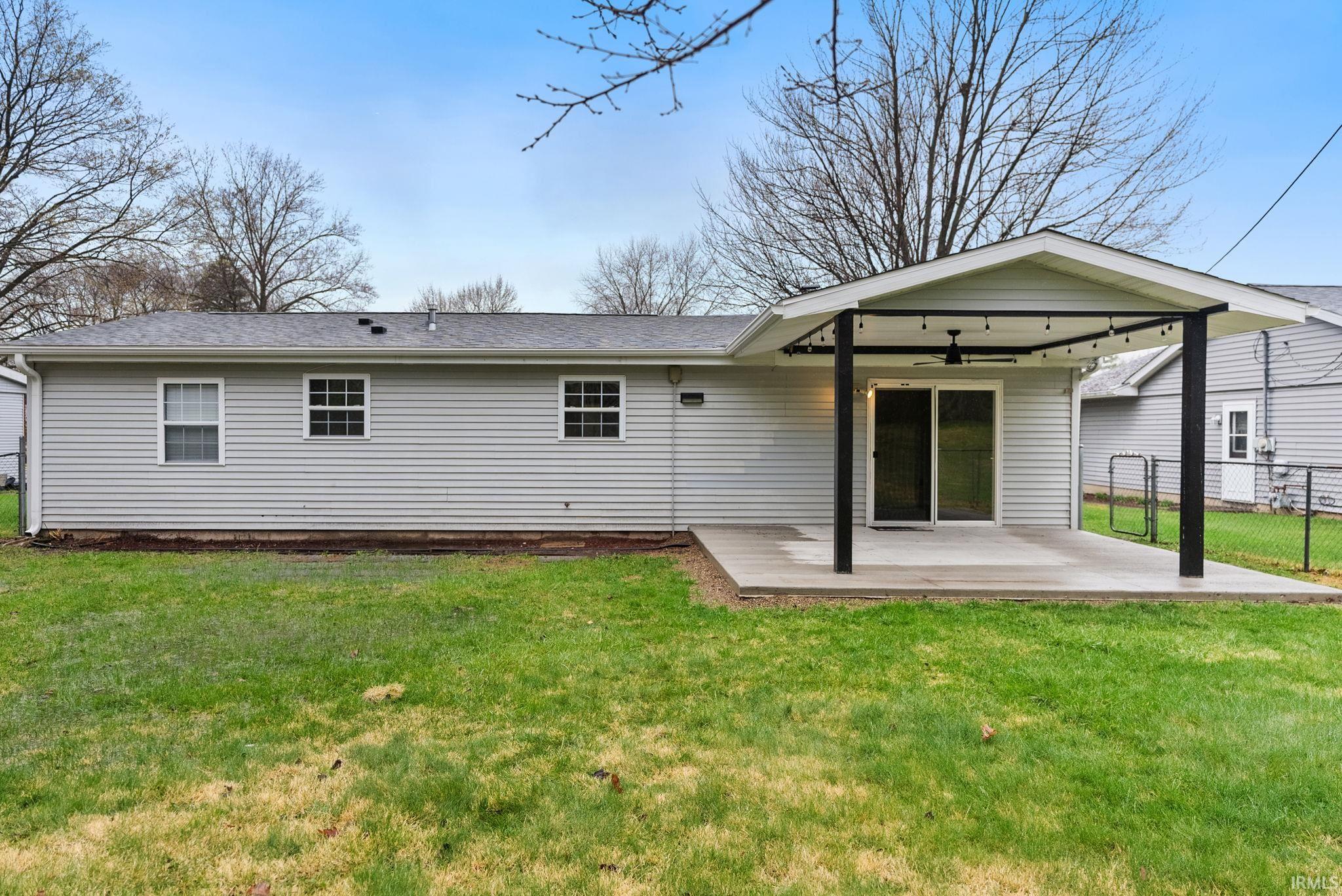 Rear view of property featuring ceiling fan, a patio, and a shingled roof