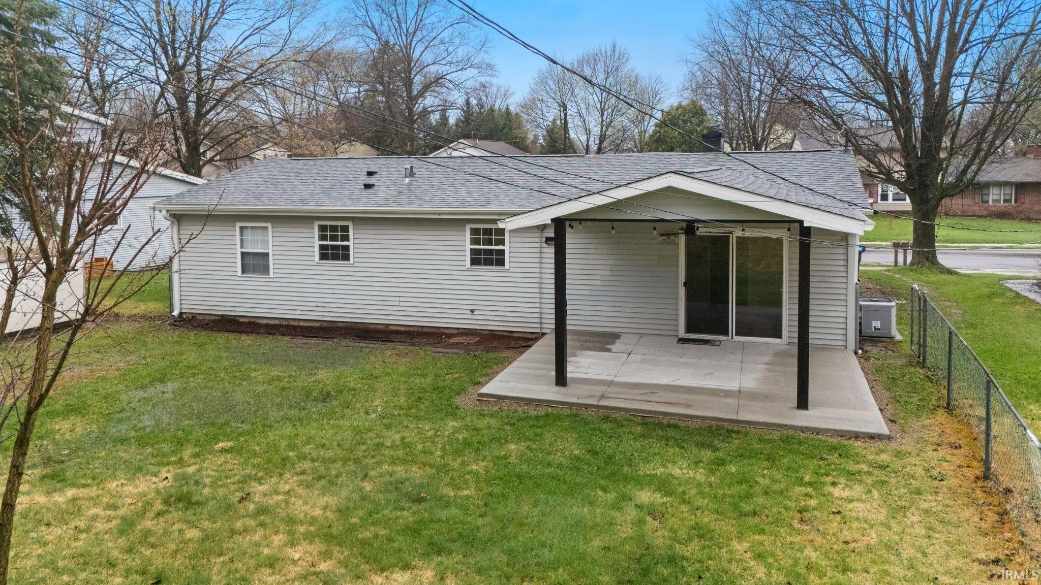 Rear view of house featuring a patio and a shingled roof