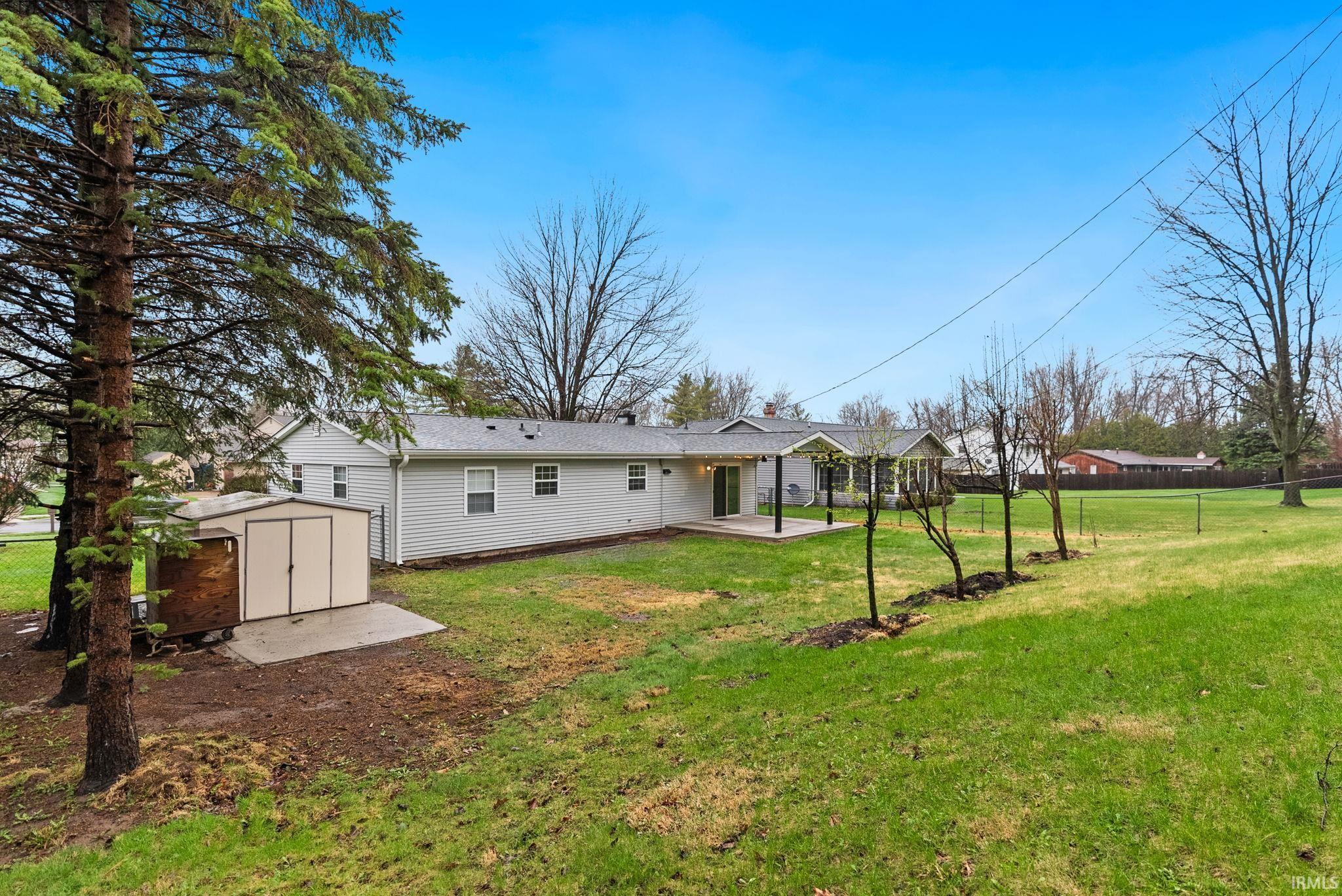 Rear view of property featuring a patio and a storage unit
