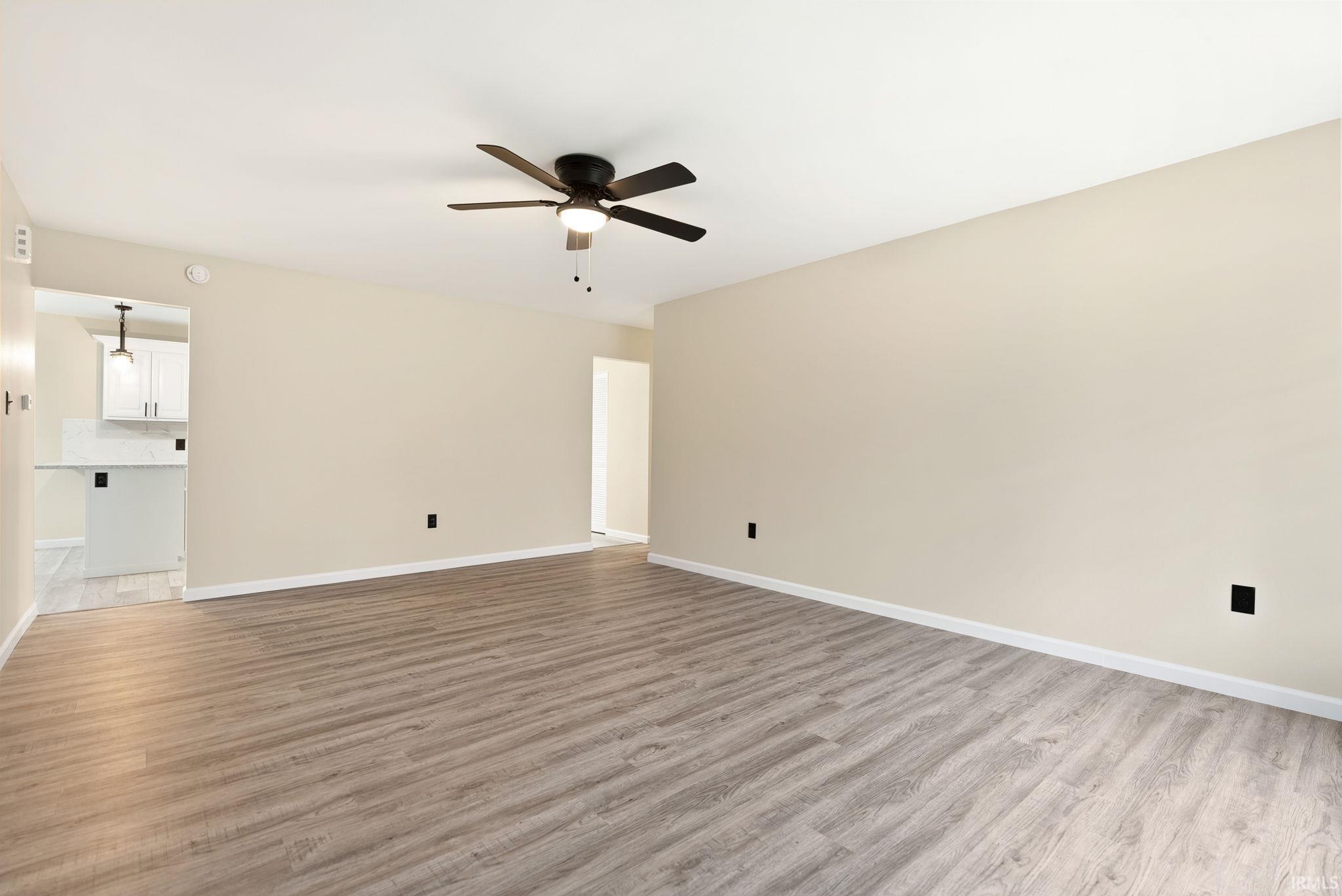 Unfurnished living room featuring a ceiling fan and light wood-style flooring