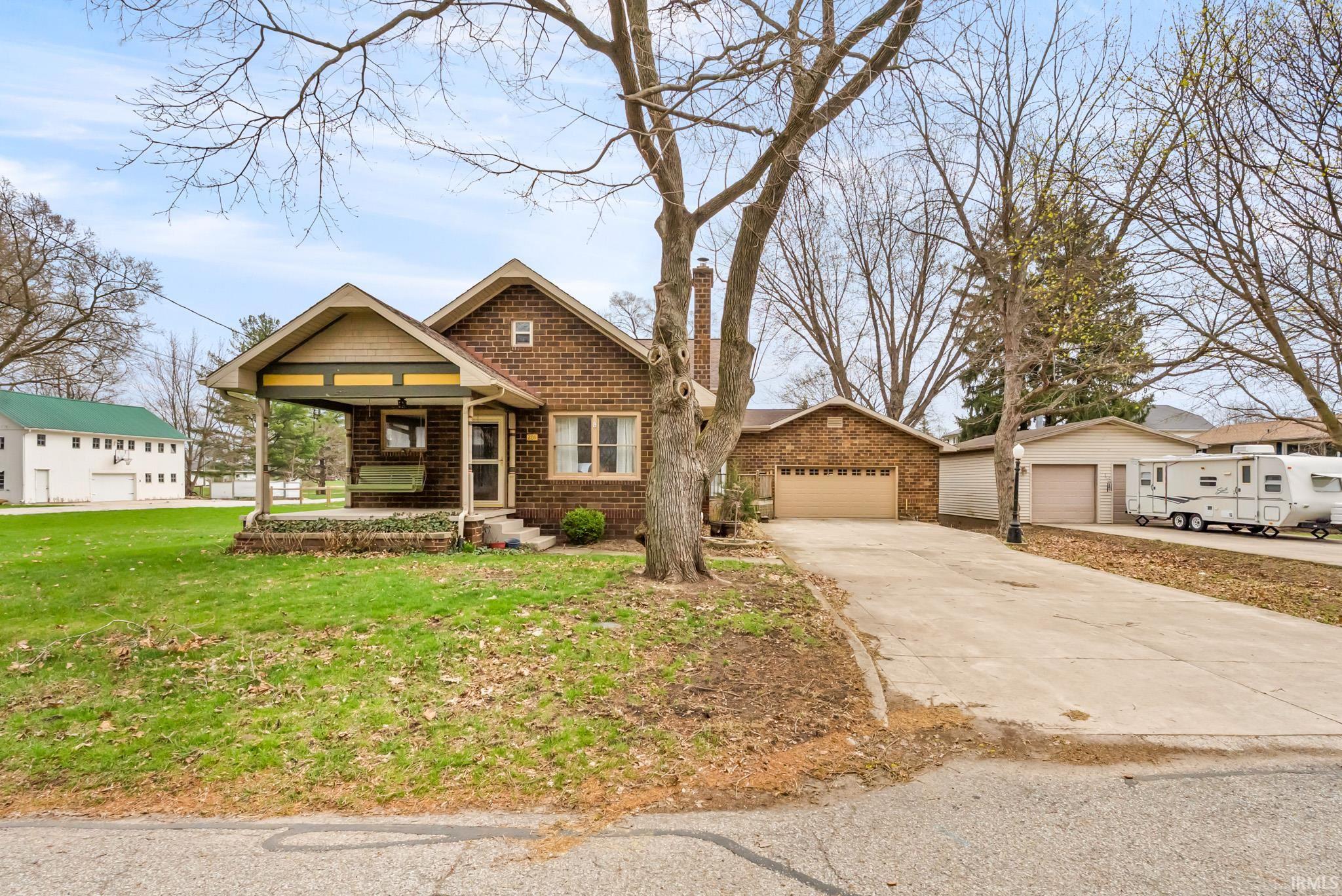 View of front of house with concrete driveway, brick siding, a front yard, and a garage