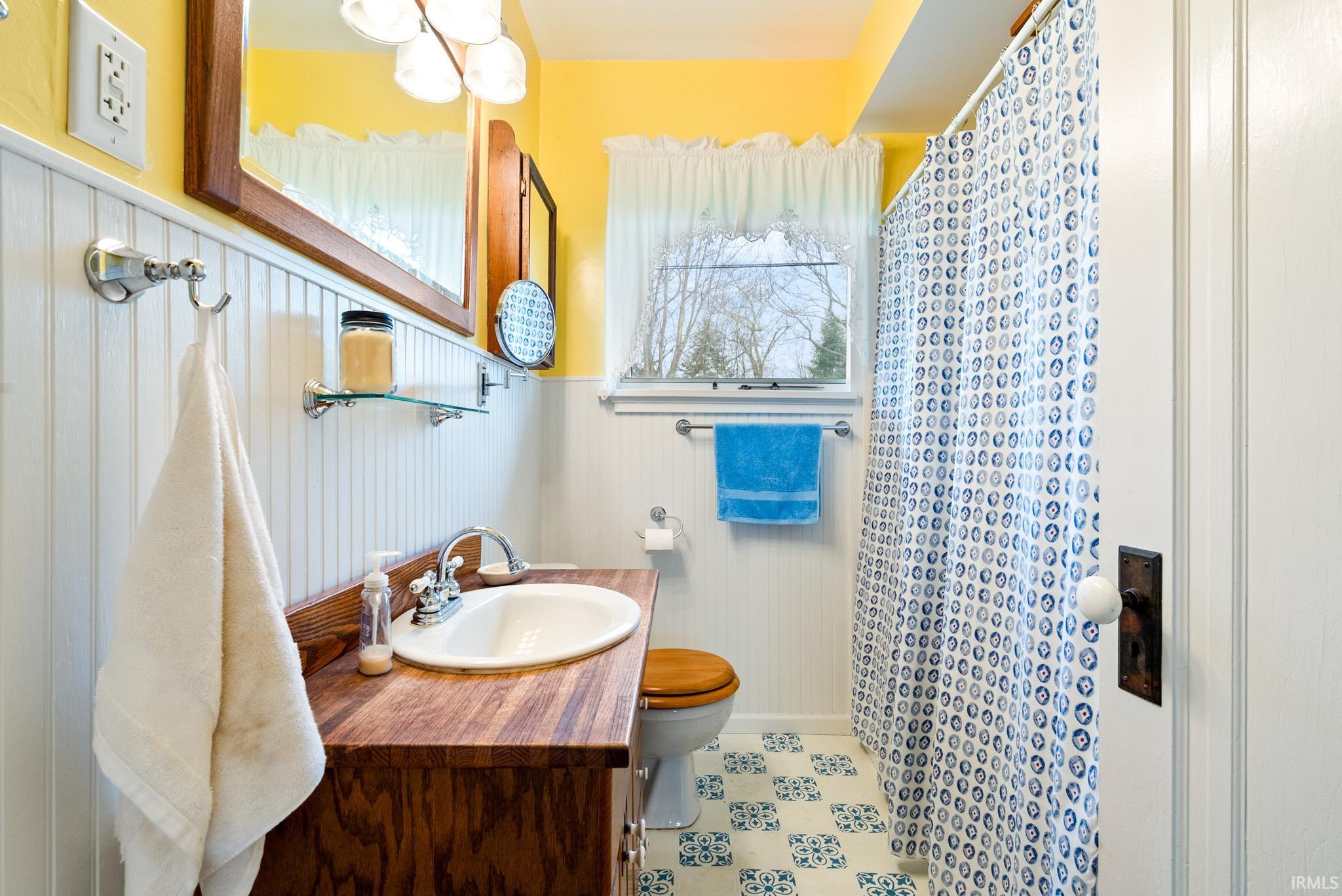 Bathroom with a shower with curtain, vanity, and wainscoting