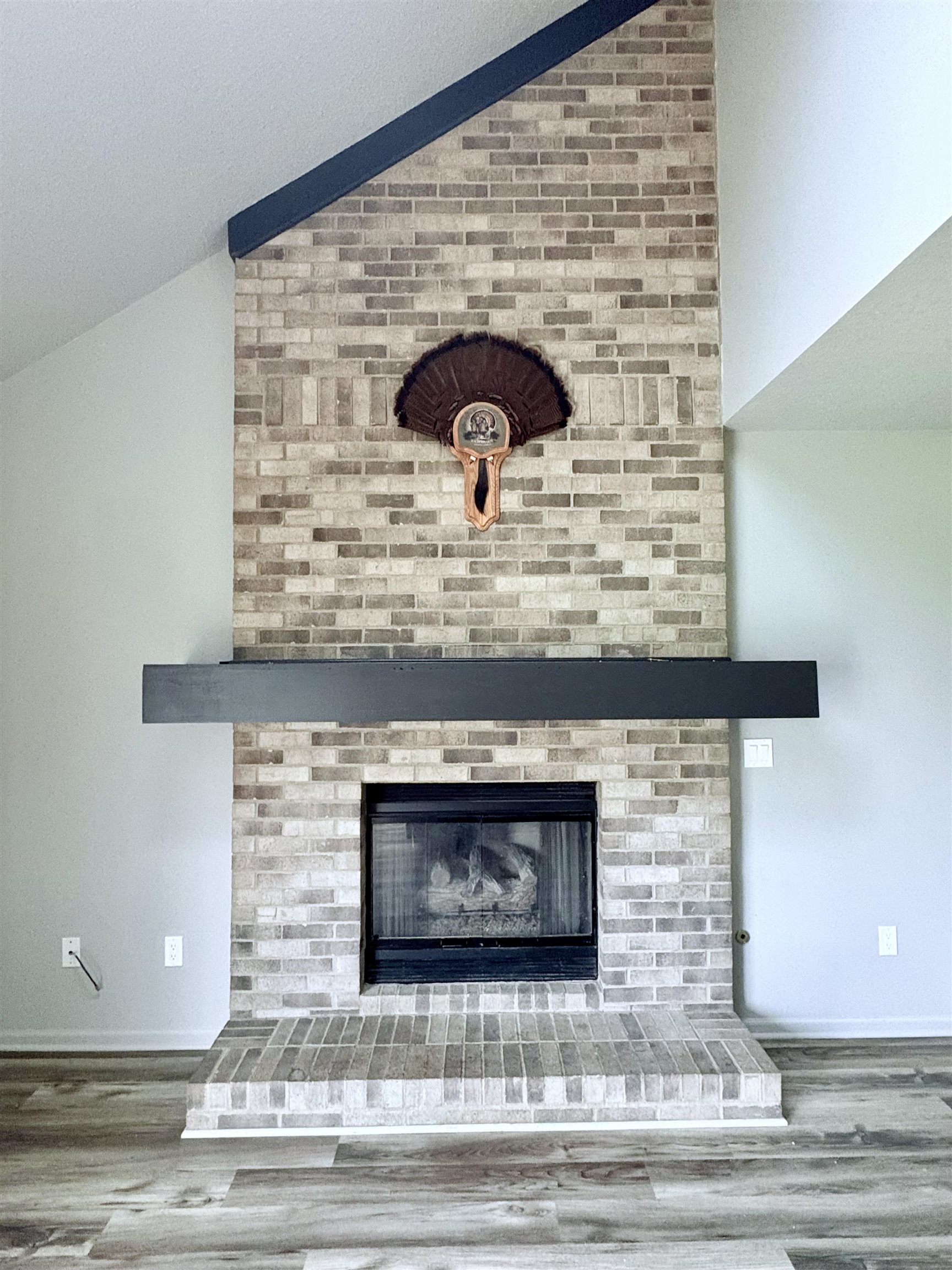Detailed view of wood finished floors and a brick fireplace