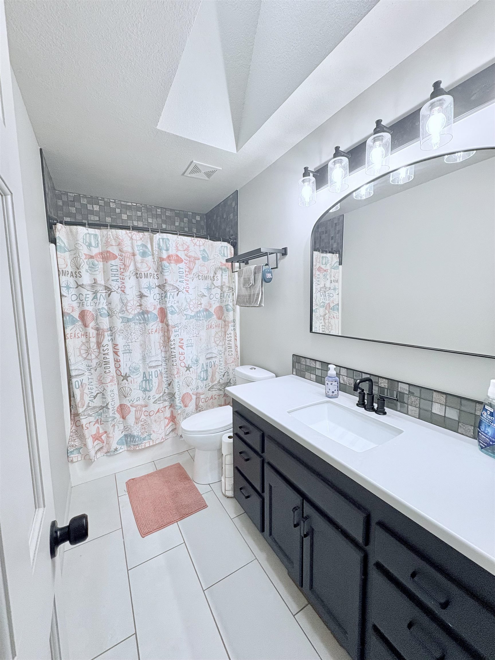 Full bathroom featuring vanity, light tile patterned floors, a textured ceiling, and shower / bath combo with shower curtain