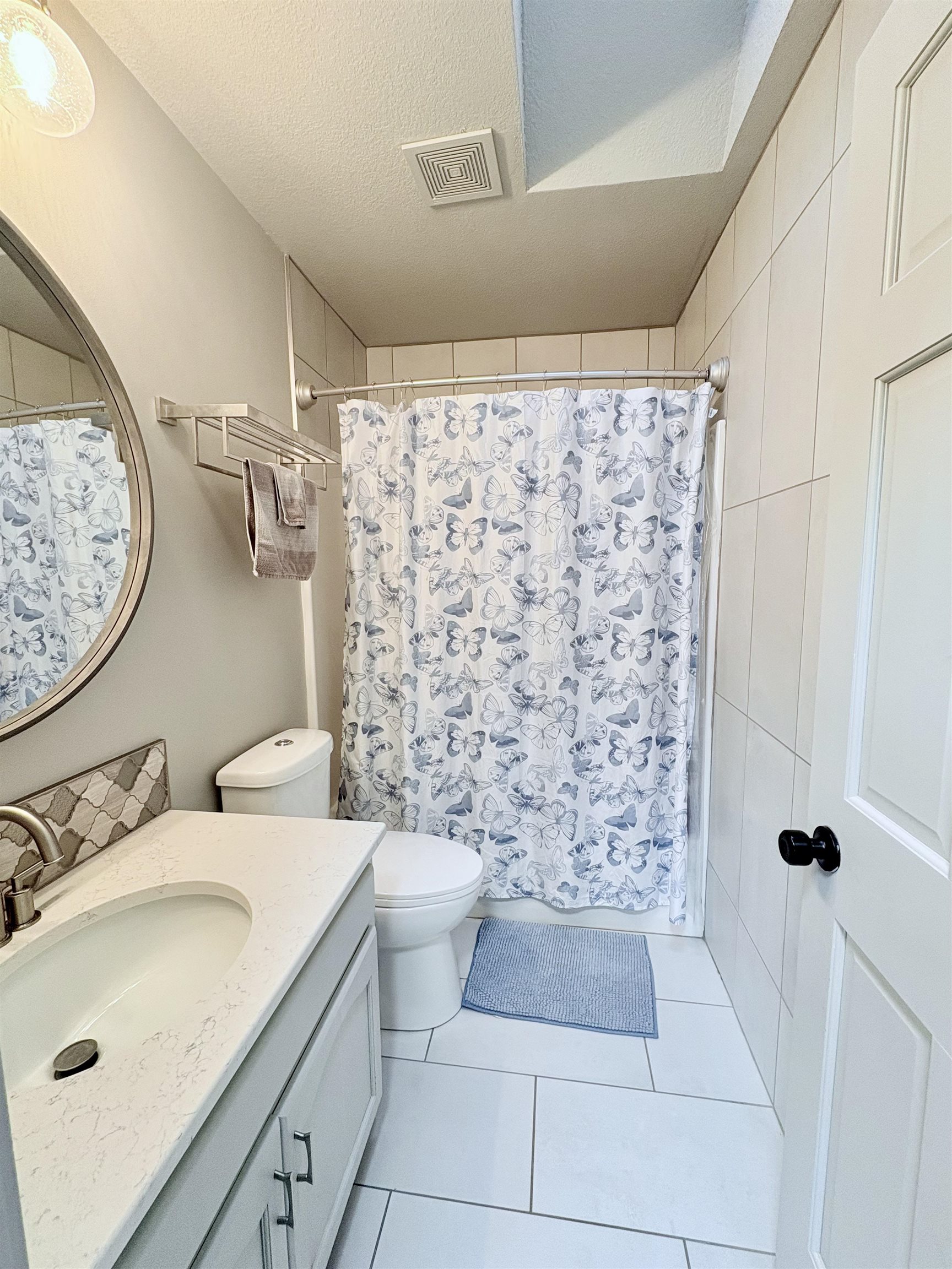 Bathroom featuring vanity, a shower with curtain, a textured ceiling, and light tile patterned flooring