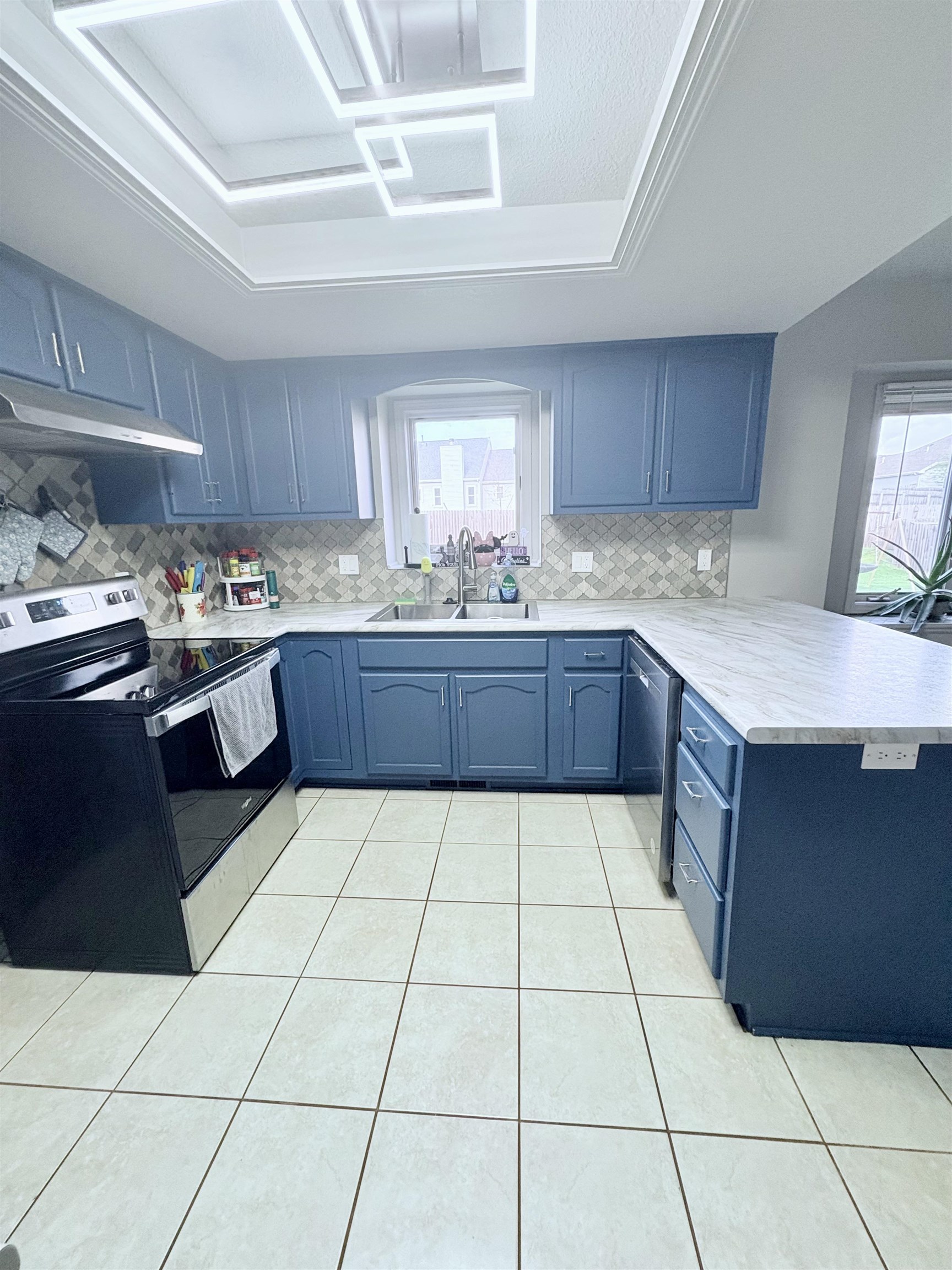 Kitchen with a peninsula, light countertops, stainless steel appliances, and tasteful backsplash
