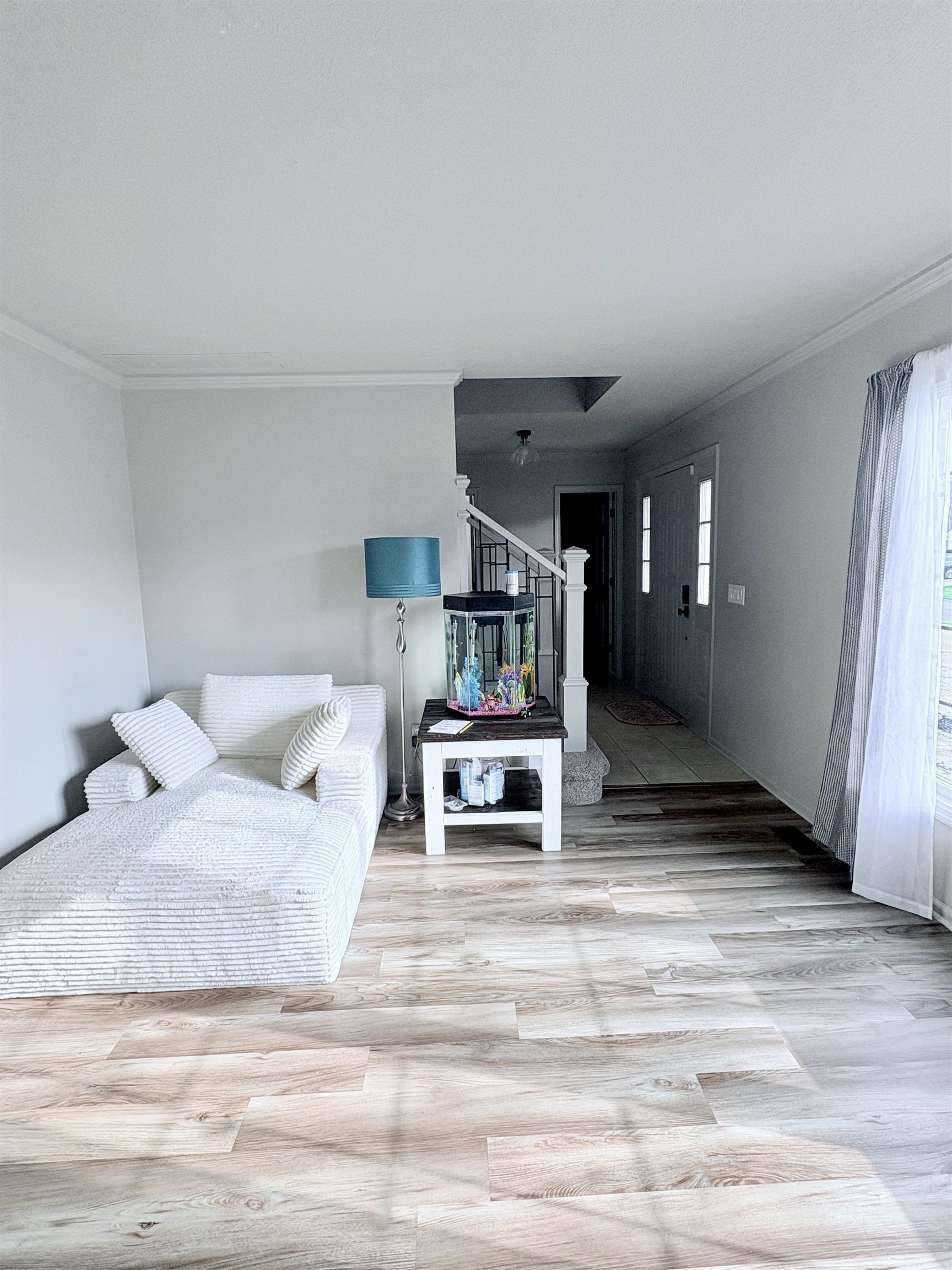 Living area with ornamental molding and light wood-style floors