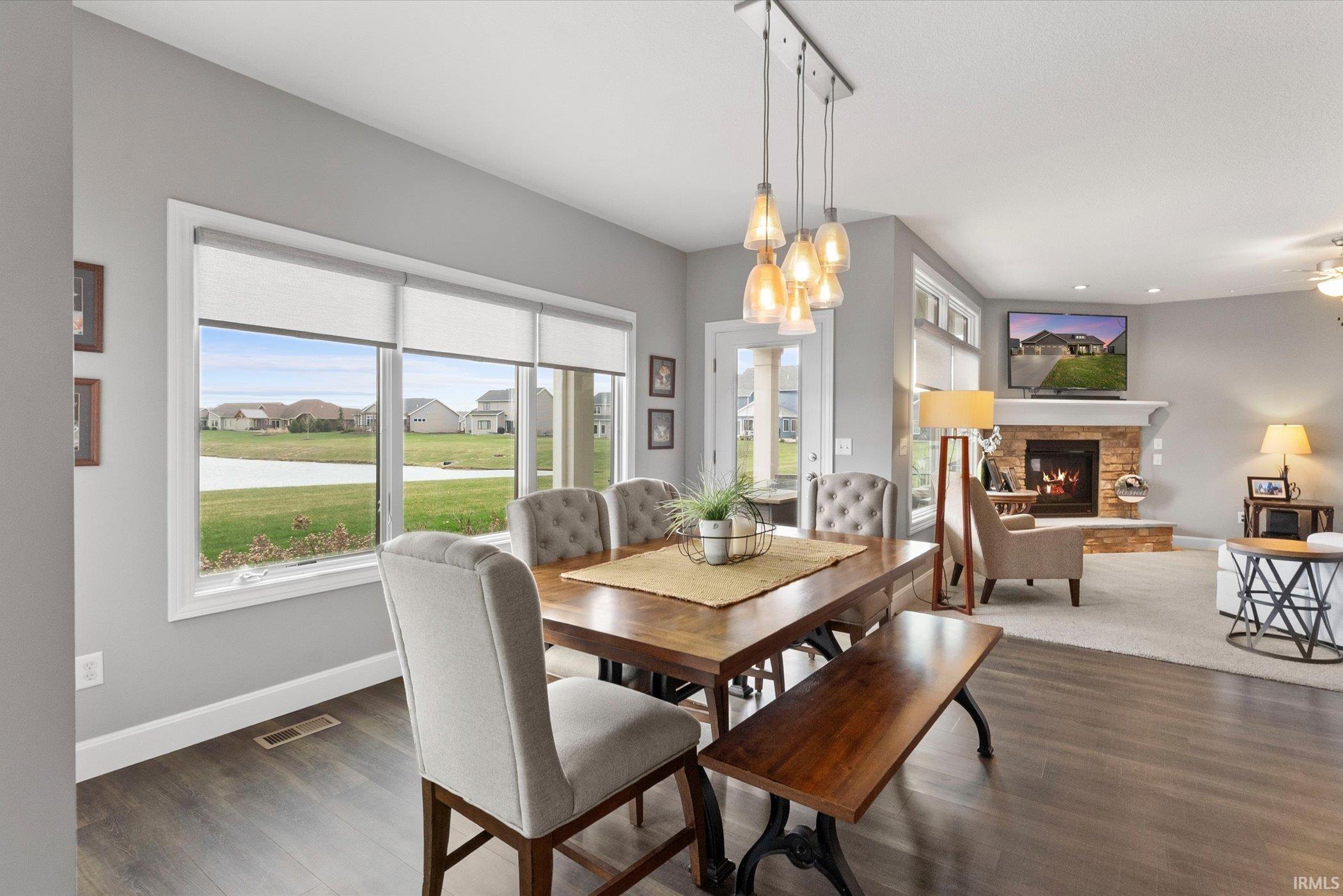 Dining room featuring dark wood-style floors, a stone fireplace, and a residential view
