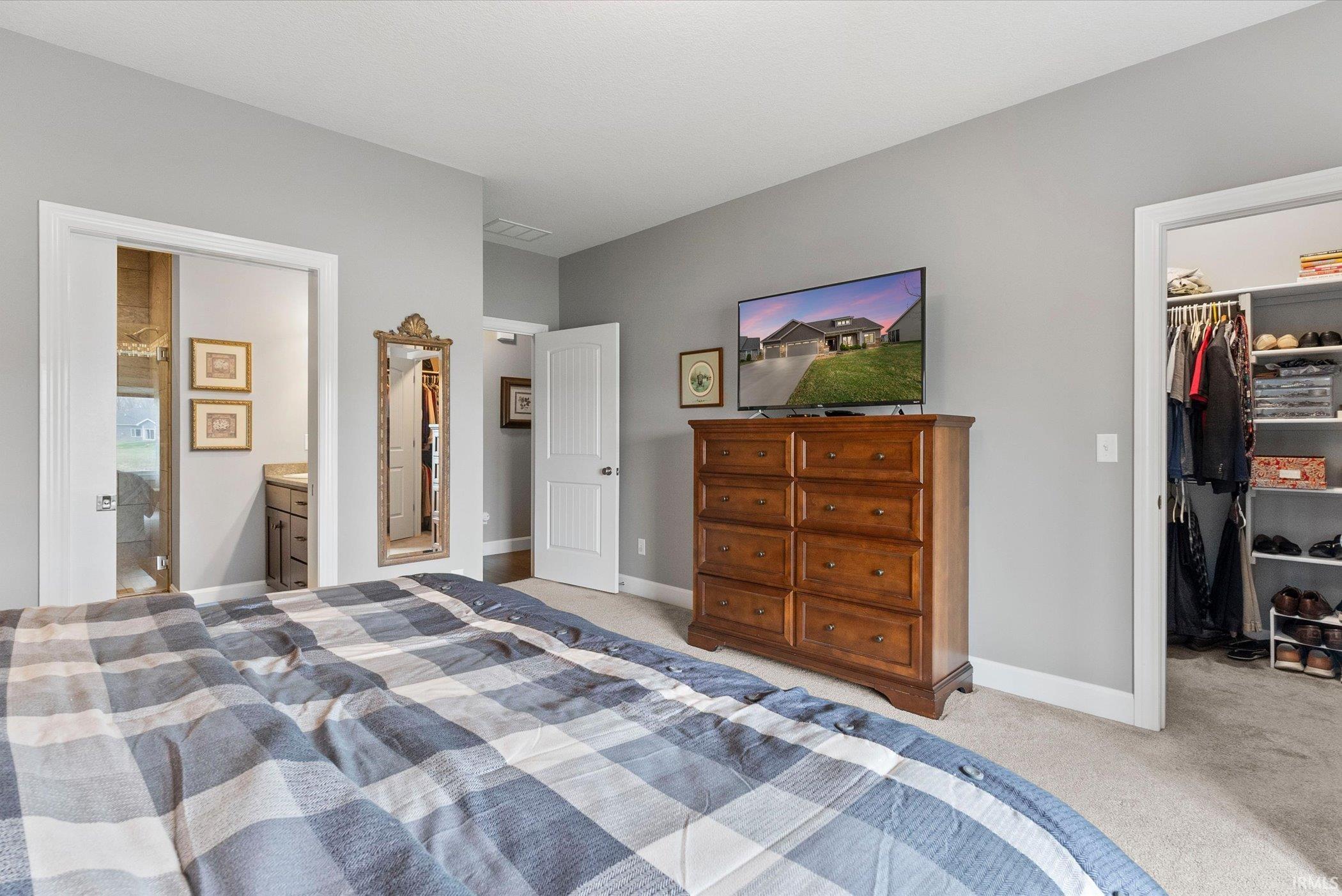 Bedroom with a spacious closet, light colored carpet, and connected bathroom