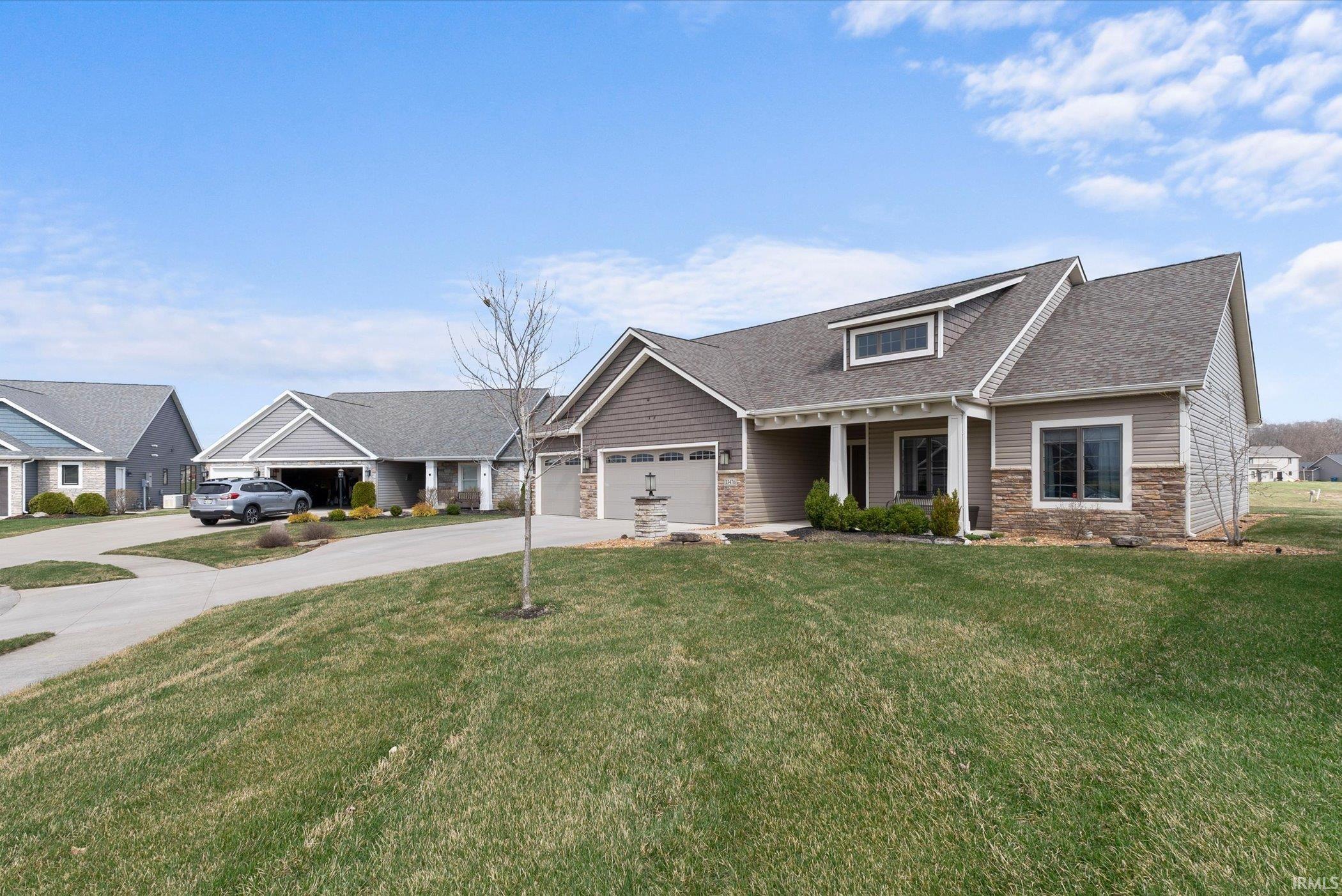 Craftsman-style house featuring stone siding, driveway, a front lawn, a shingled roof, and a porch