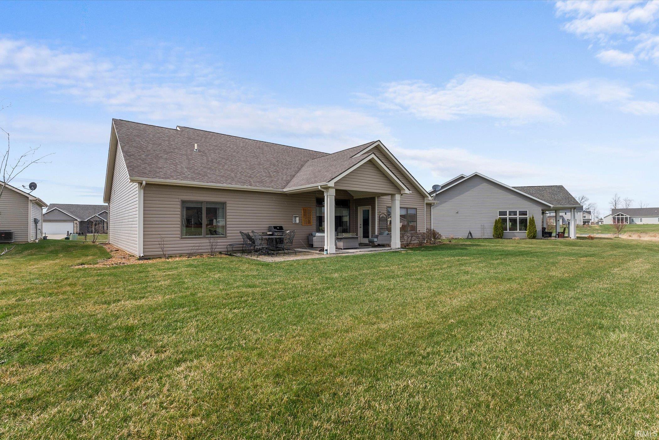 Back of property with a patio, roof with shingles, and a lawn