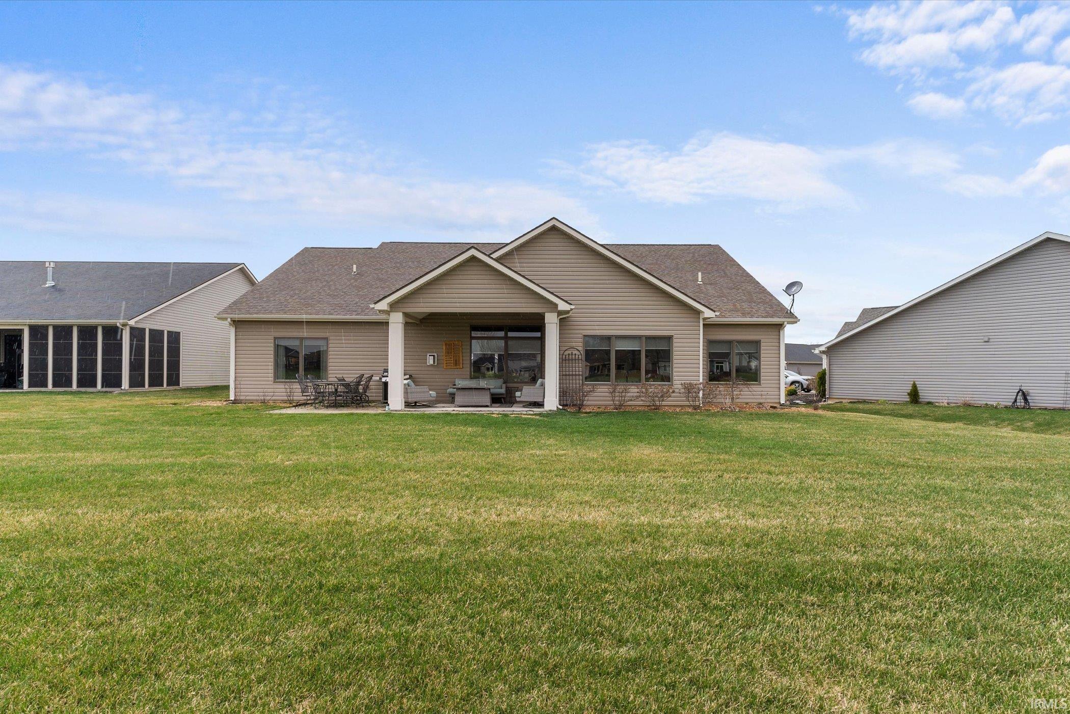Rear view of house with a patio, a shingled roof, and a yard