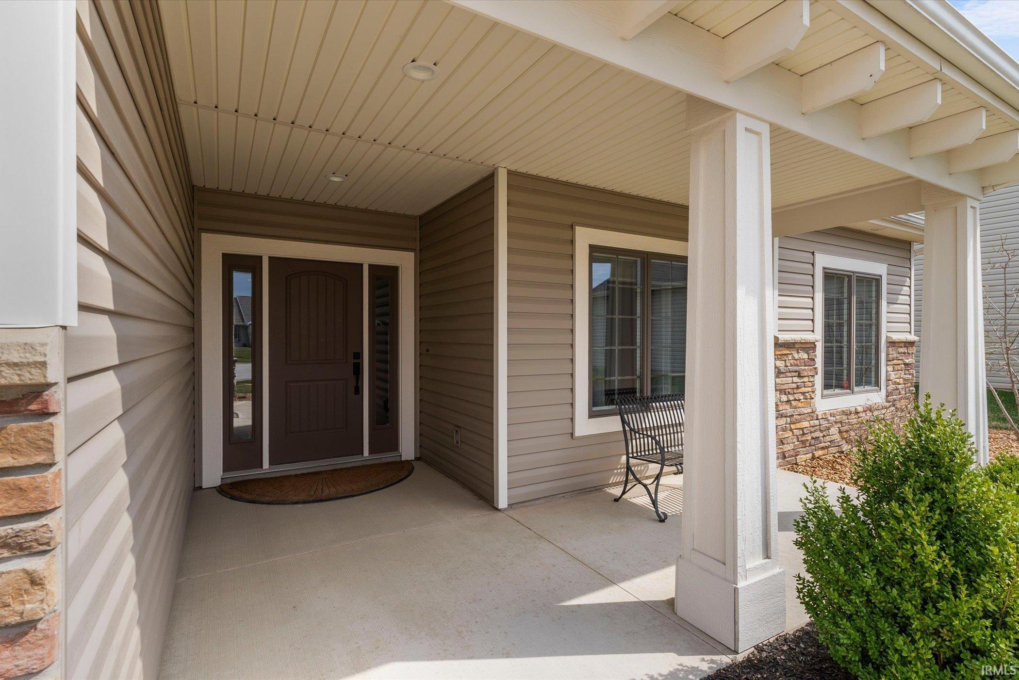 Doorway to property with stone siding and a porch