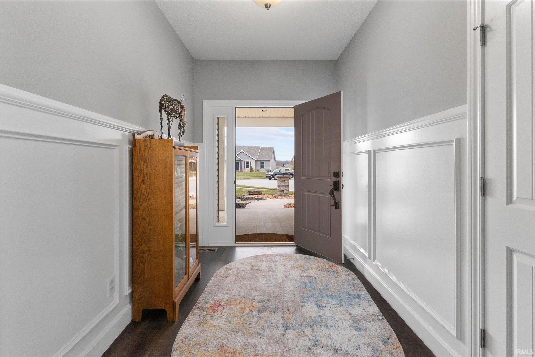 Foyer featuring dark wood-type flooring and a decorative wall