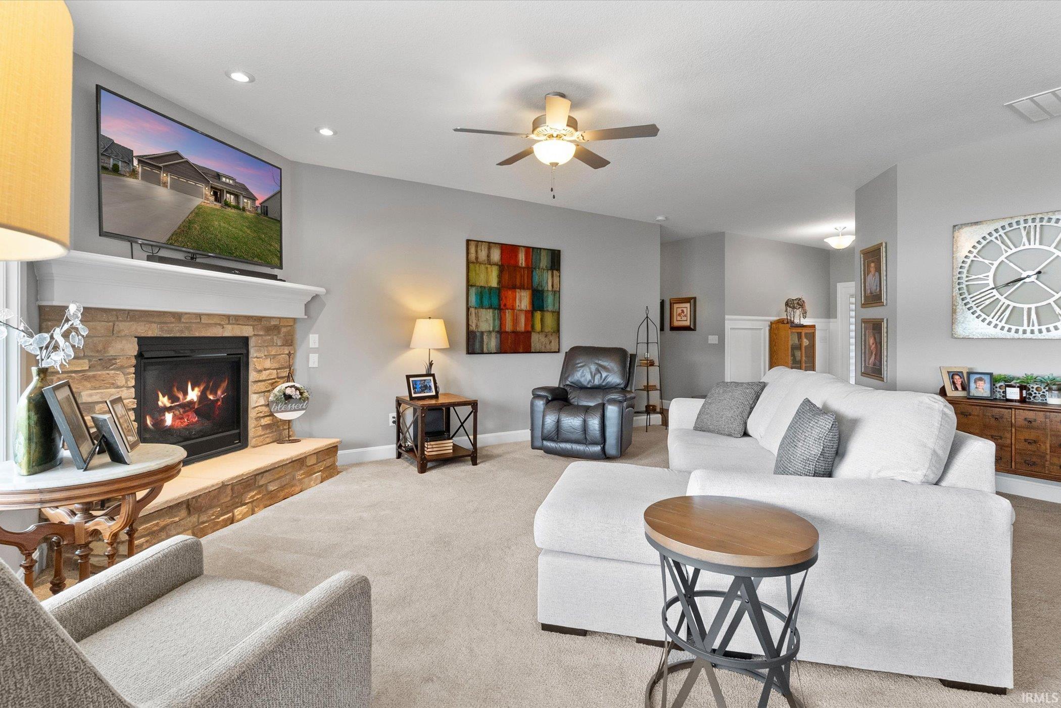 Living room with ceiling fan, a stone fireplace, carpet flooring, and recessed lighting