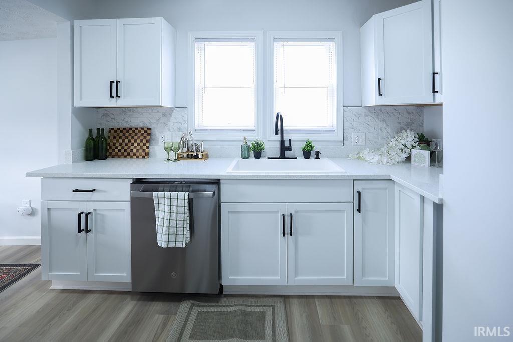 Kitchen featuring dishwasher, white cabinetry, light wood finished floors, tasteful backsplash, and light stone countertops