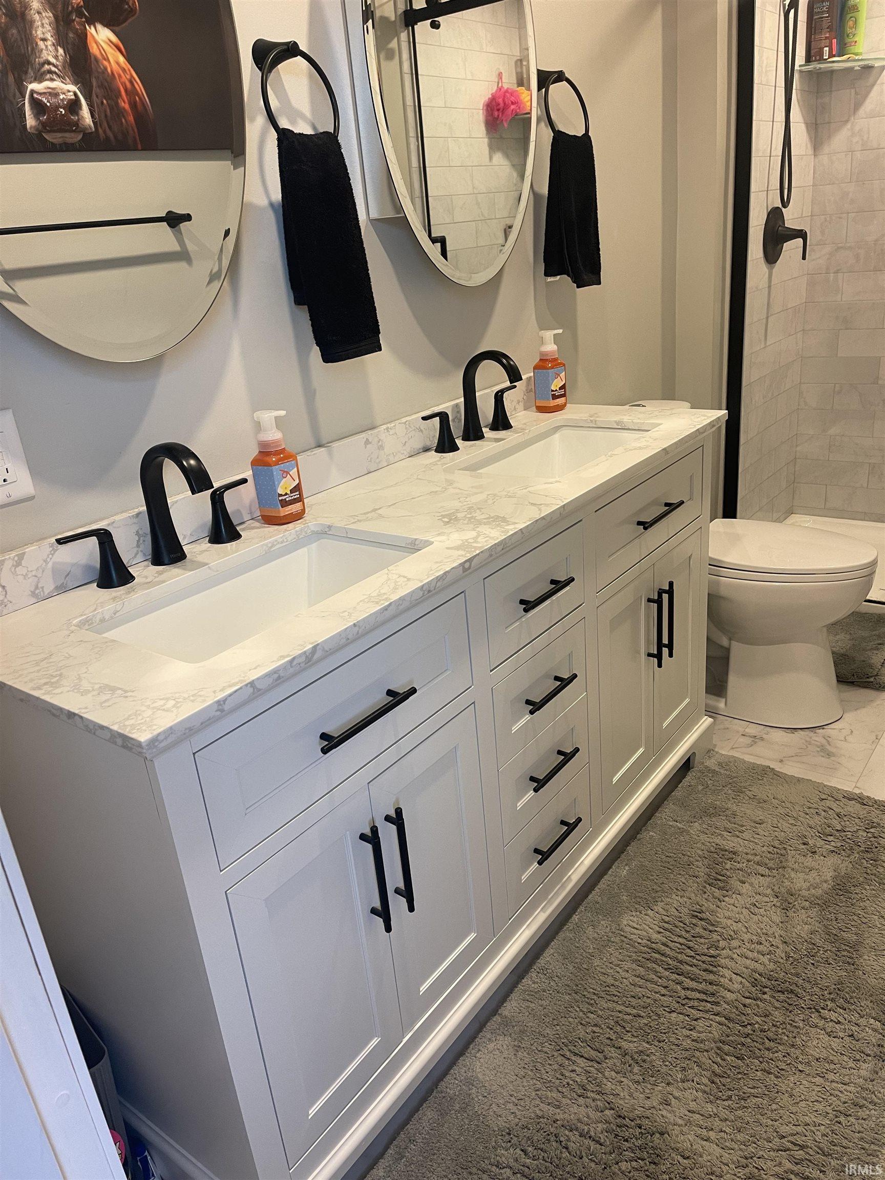 Bathroom featuring double vanity and a tile shower