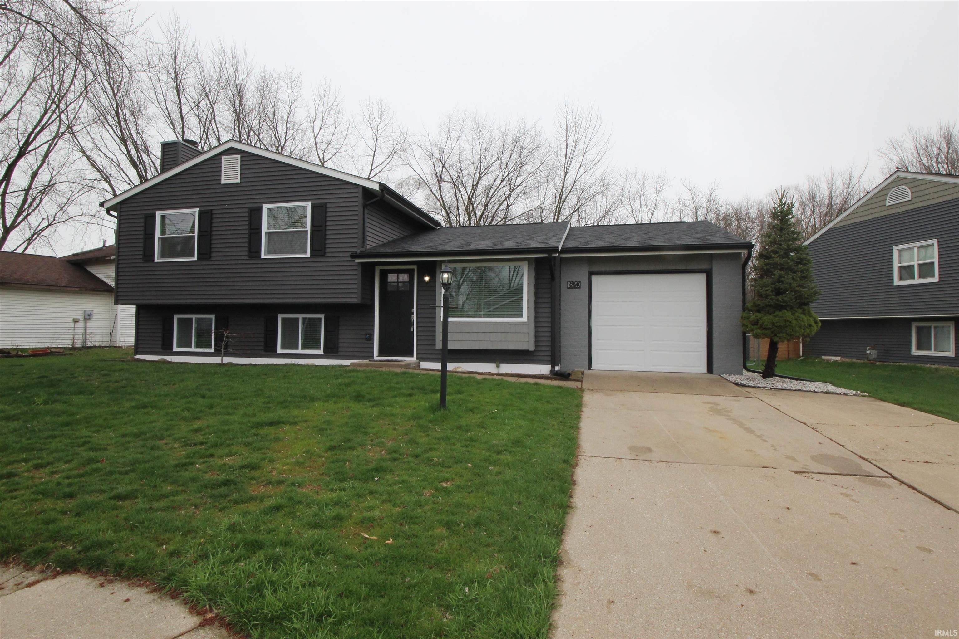 Tri-level home featuring concrete driveway, a front yard, and a garage