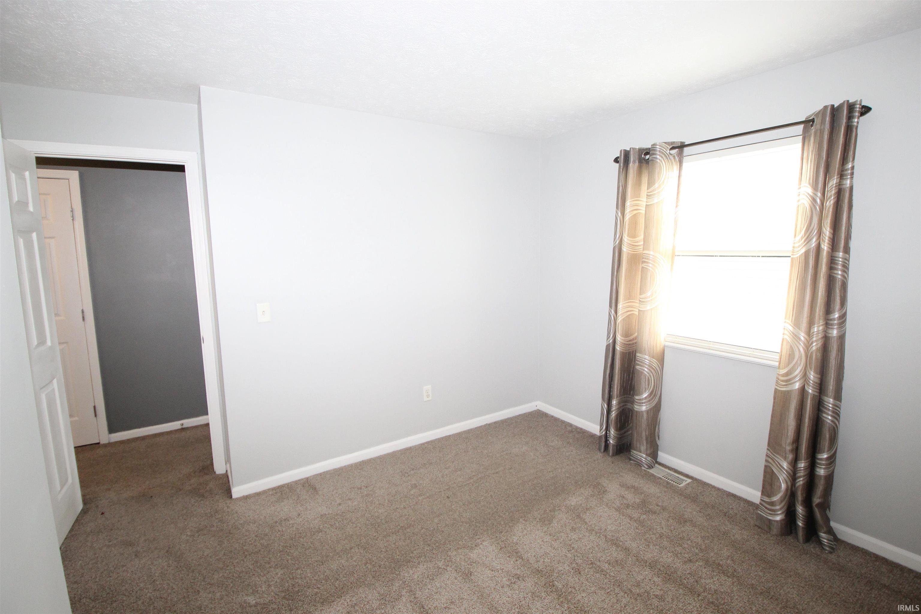 Unfurnished room featuring dark colored carpet