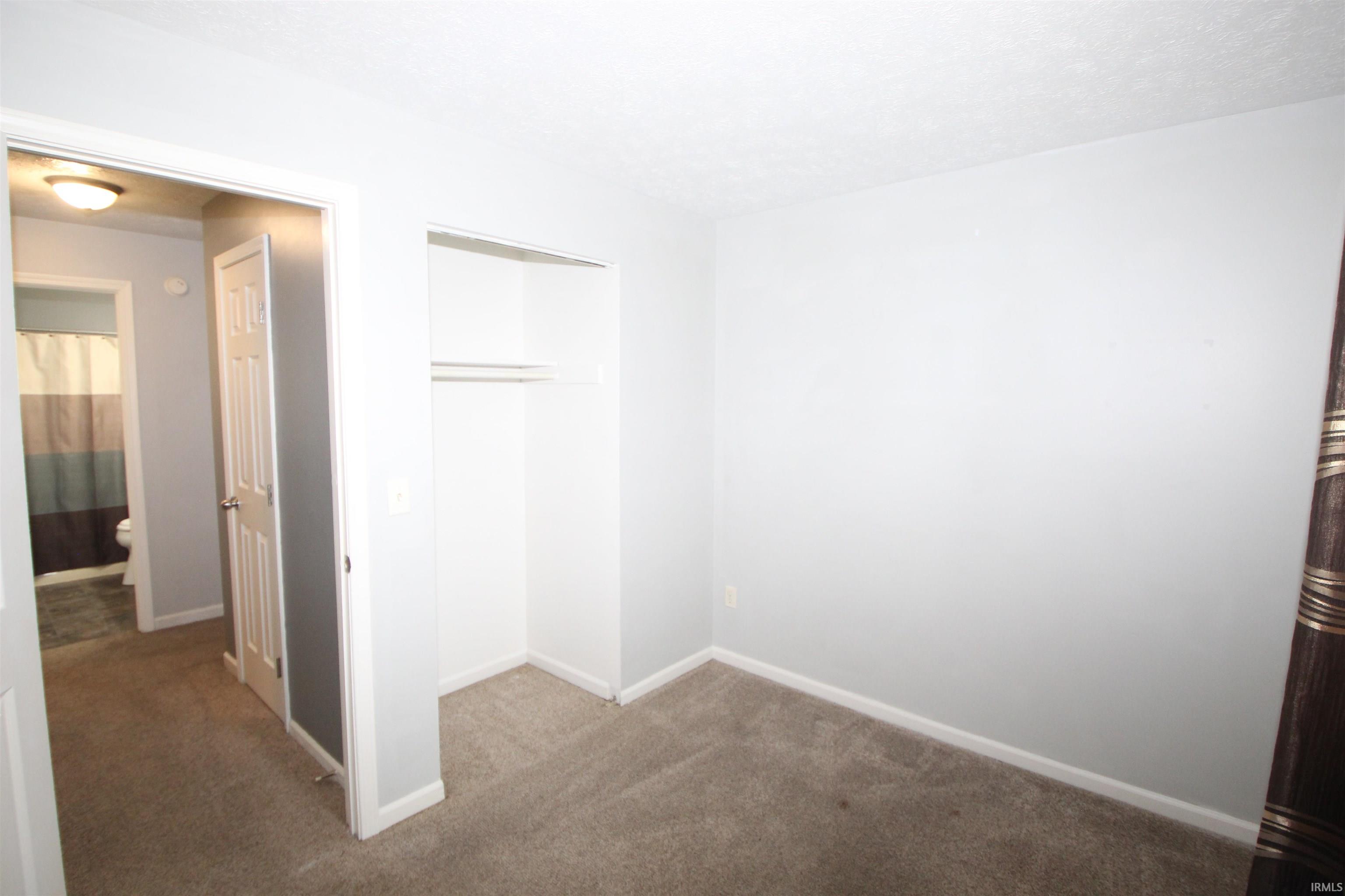 Unfurnished bedroom with dark carpet and a closet