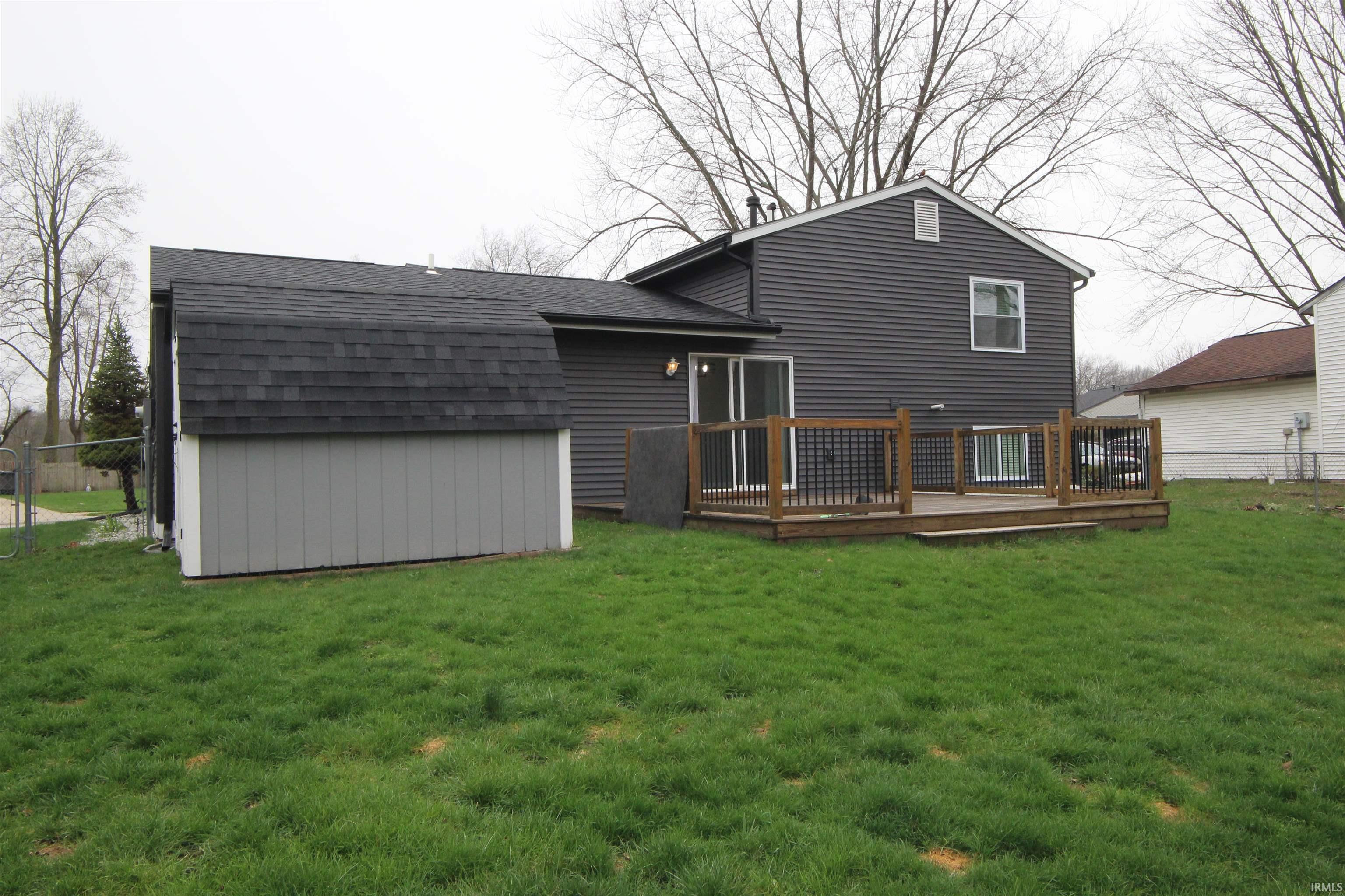 Back of house featuring a shingled roof and a deck
