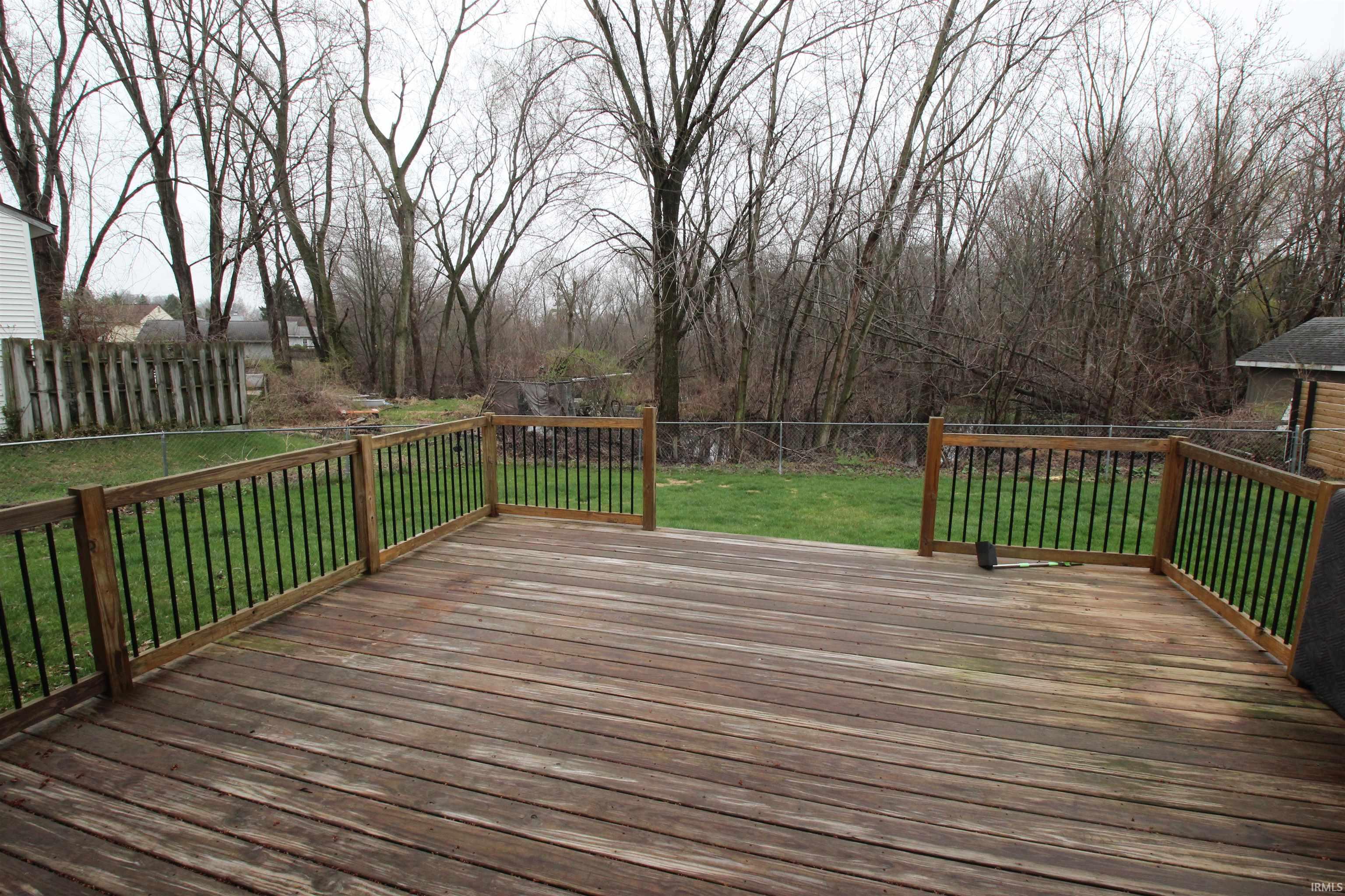 Wooden terrace with a fenced backyard