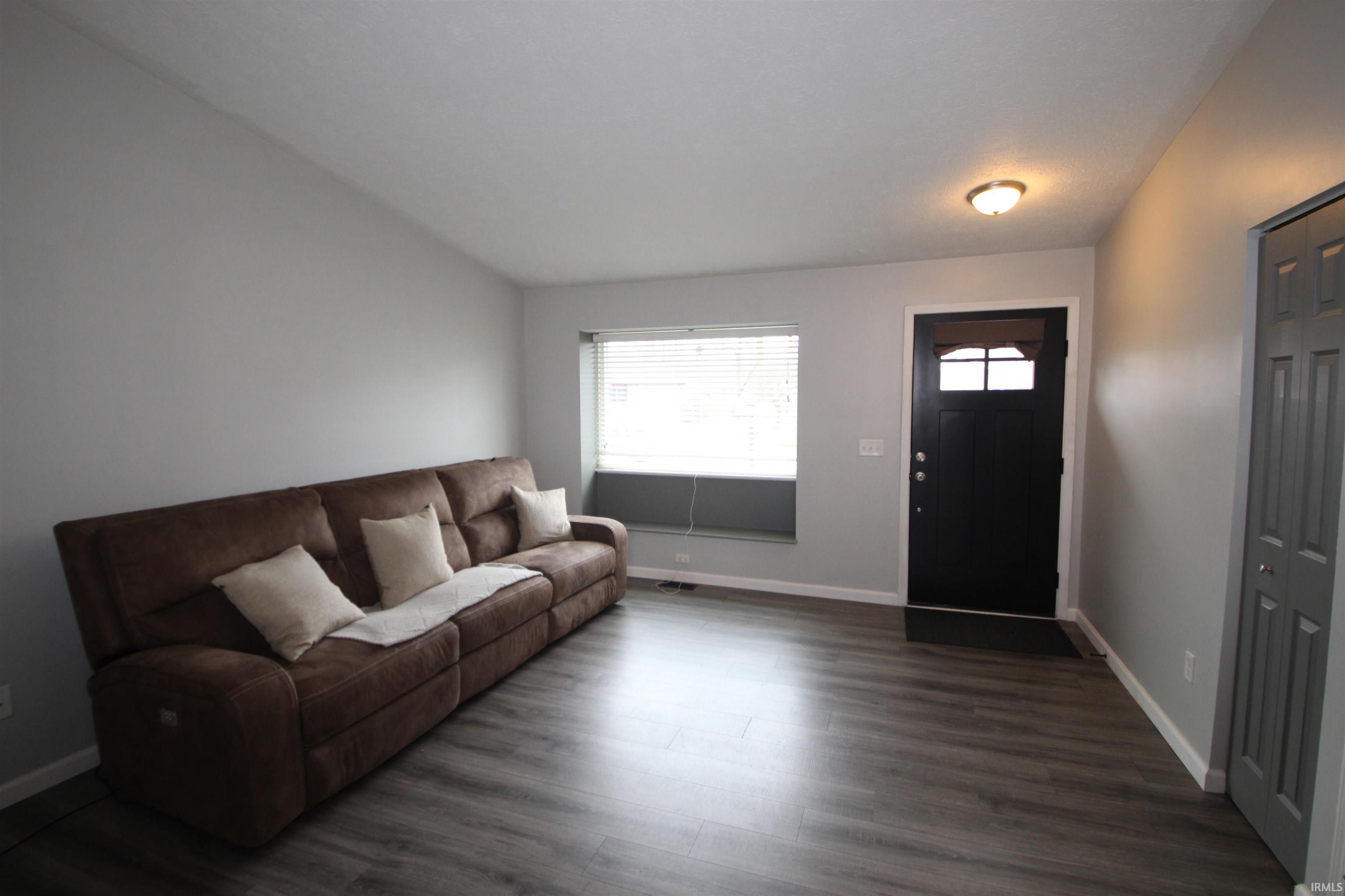 Living room featuring vaulted ceiling and dark wood finished floors