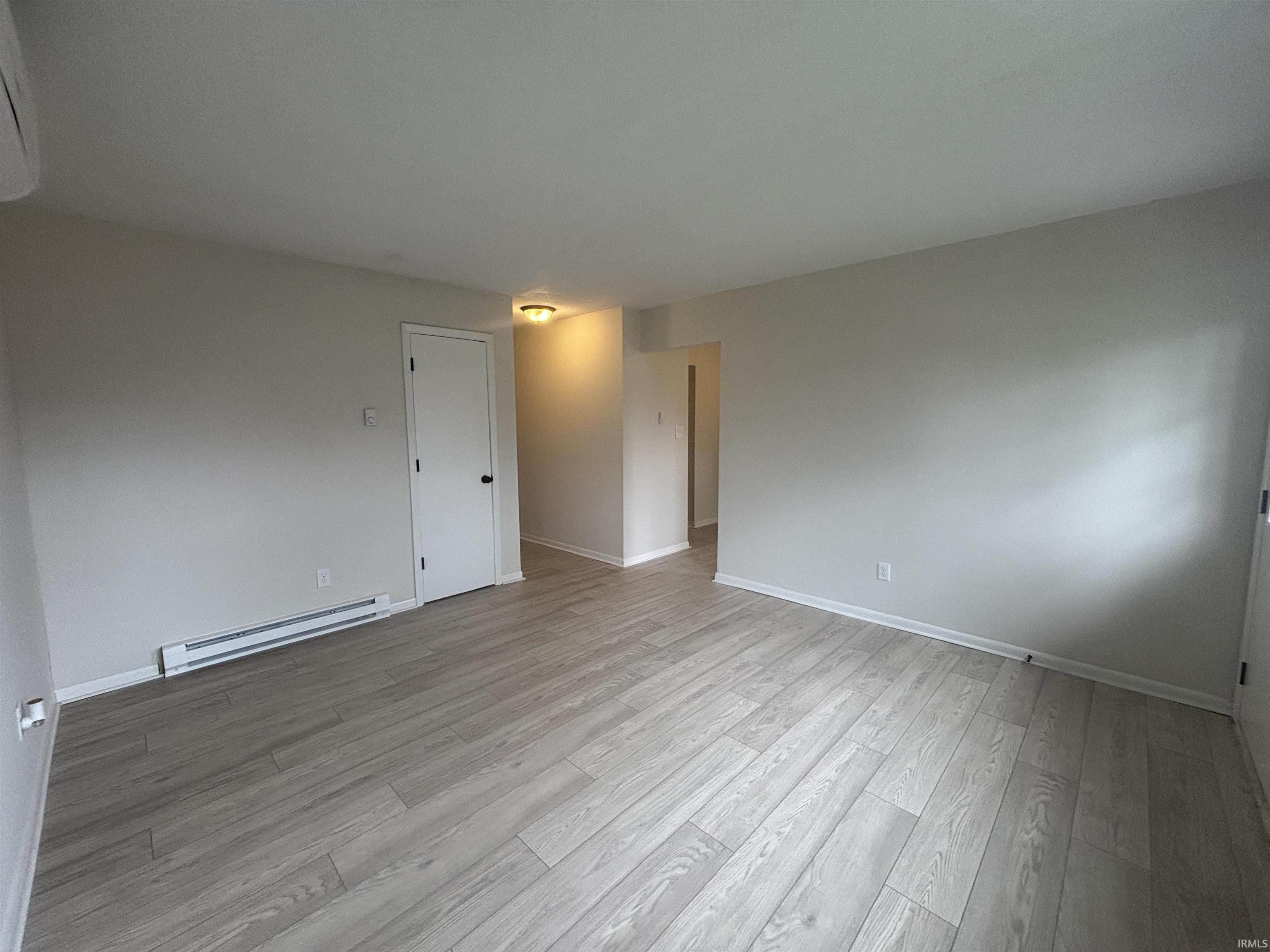 Spare room featuring a baseboard heating unit and light wood-style flooring