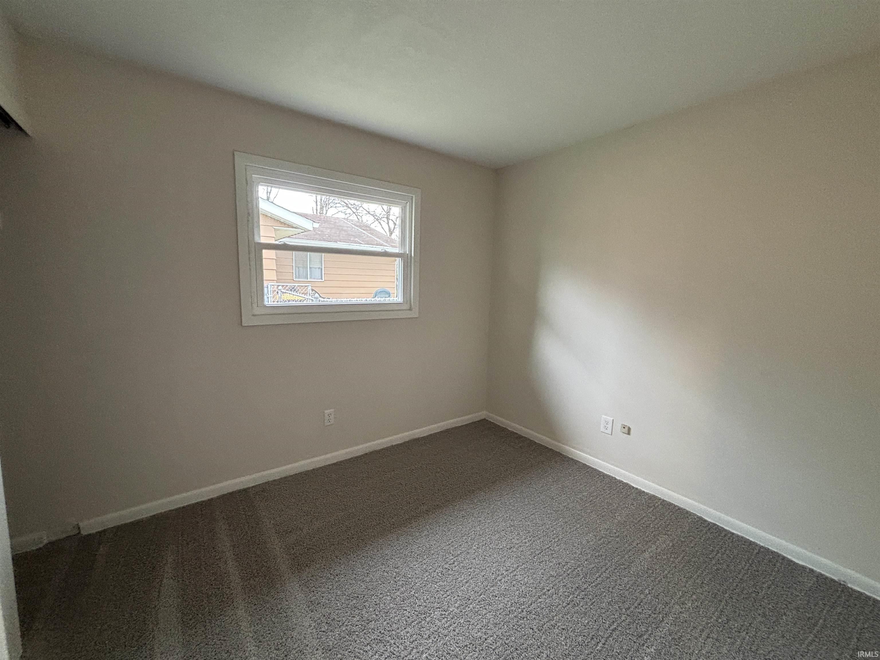 Unfurnished room featuring baseboards and dark colored carpet