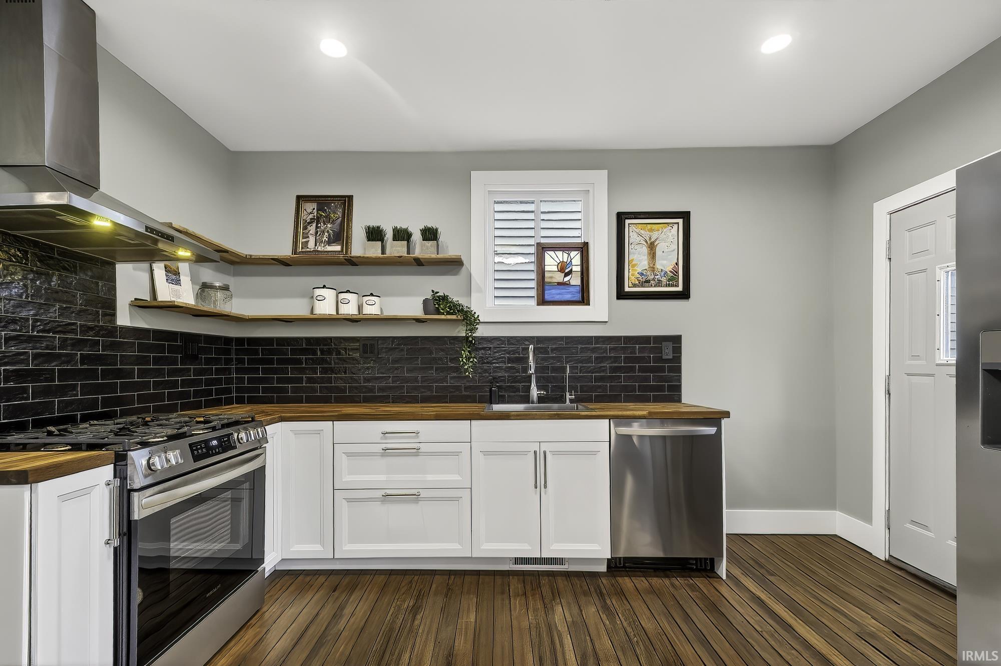 Kitchen featuring wood counters, stainless steel appliances, open shelves, backsplash, and dark wood-style floors