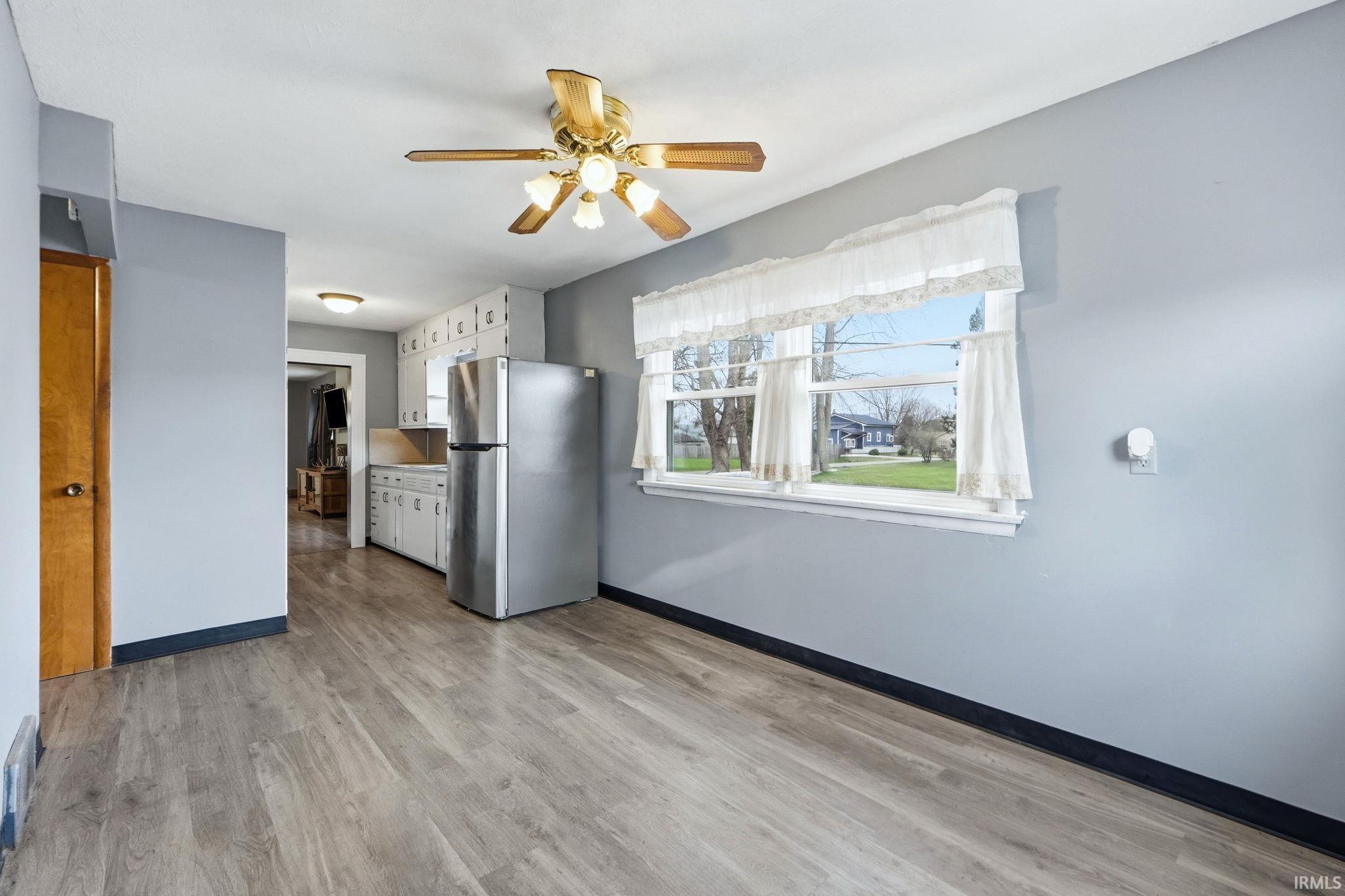 Kitchen featuring freestanding refrigerator, light wood-style floors, ceiling fan, white cabinetry, and light countertops