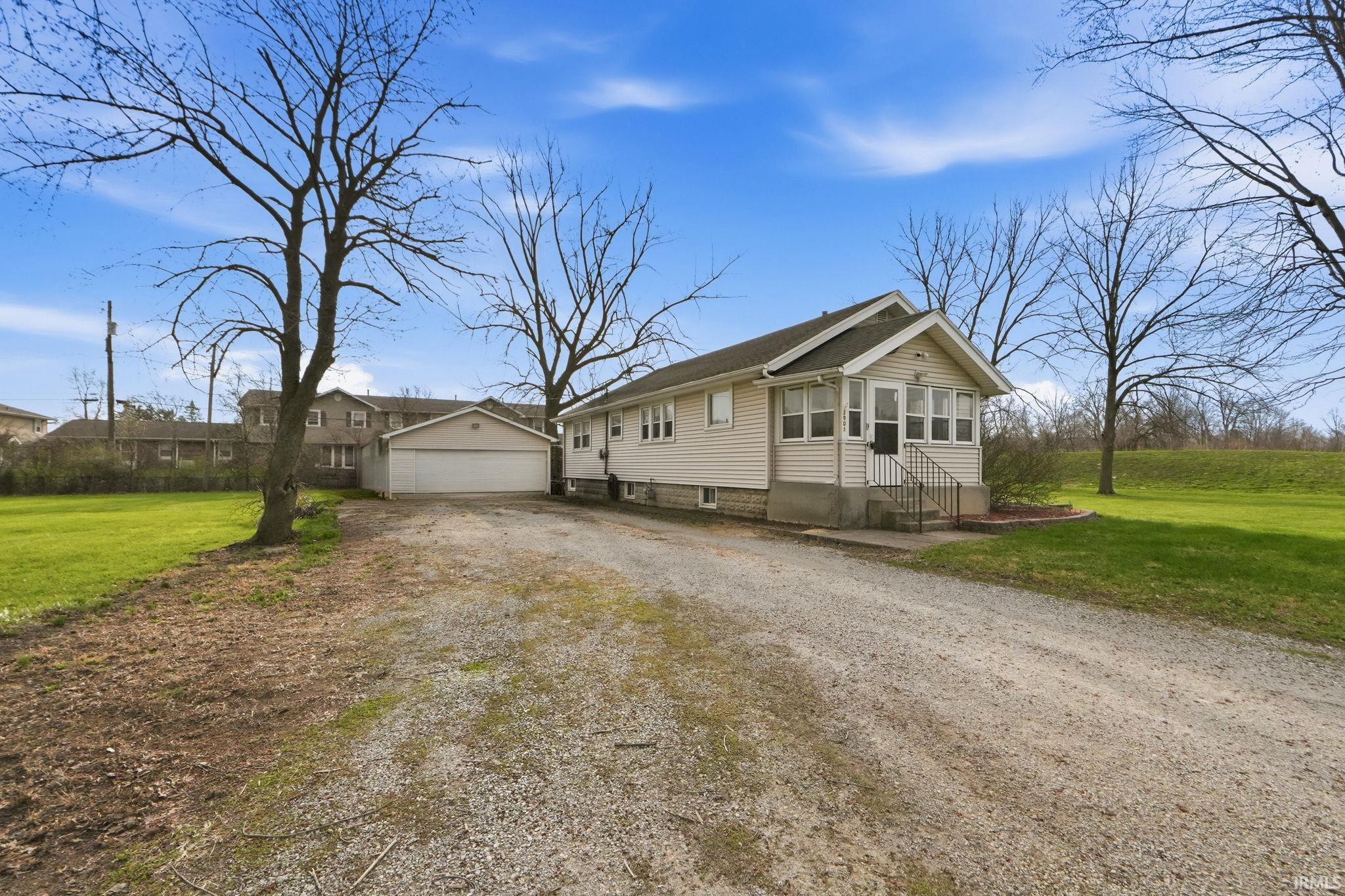 View of front of property featuring a sunroom, a front lawn, an outdoor structure, and entry steps