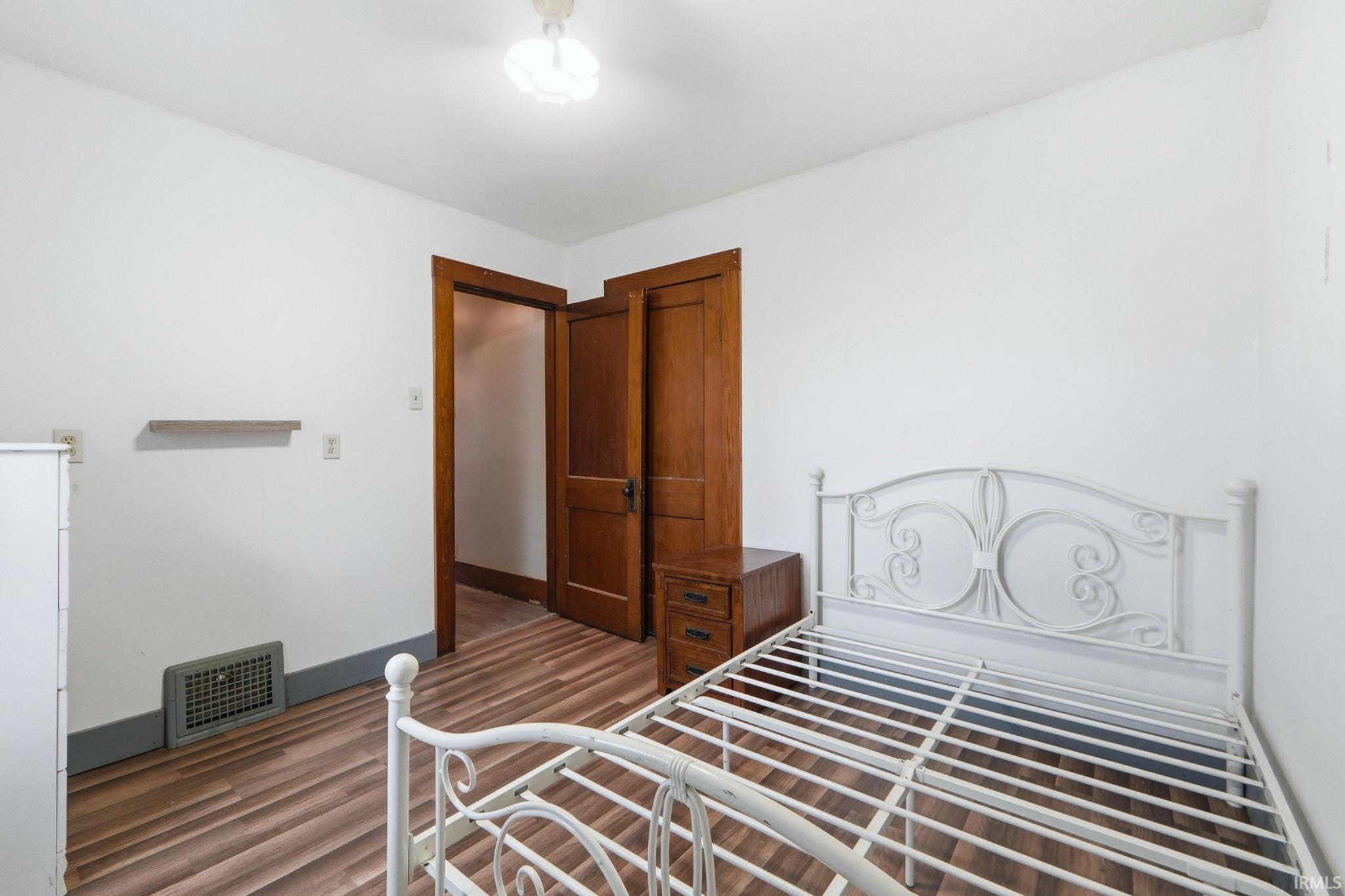 Bedroom featuring dark wood-style floors and baseboards