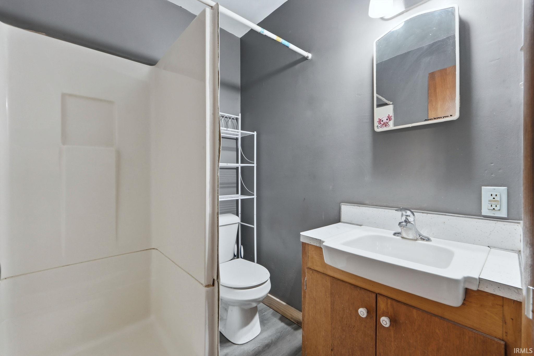 Full bathroom with vanity, a stall shower, and wood finished floors