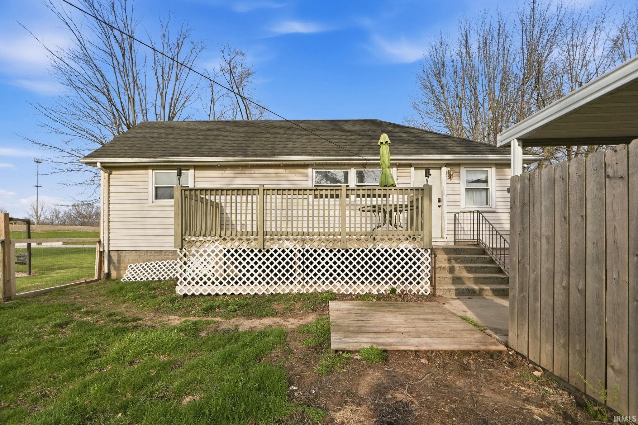 Back of property with a wooden deck and roof with shingles