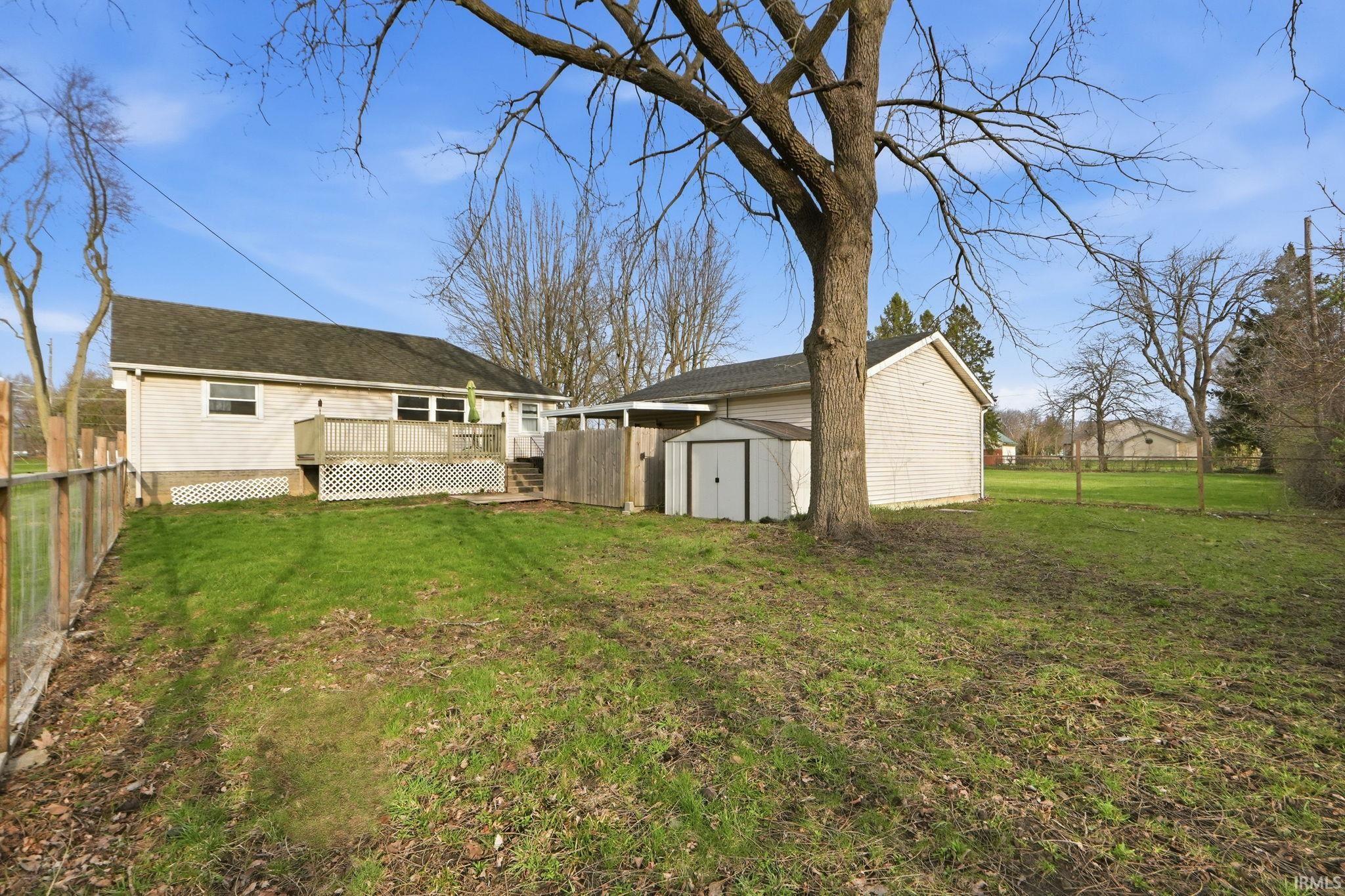 Back of house featuring a wooden deck, a fenced backyard, and a storage shed