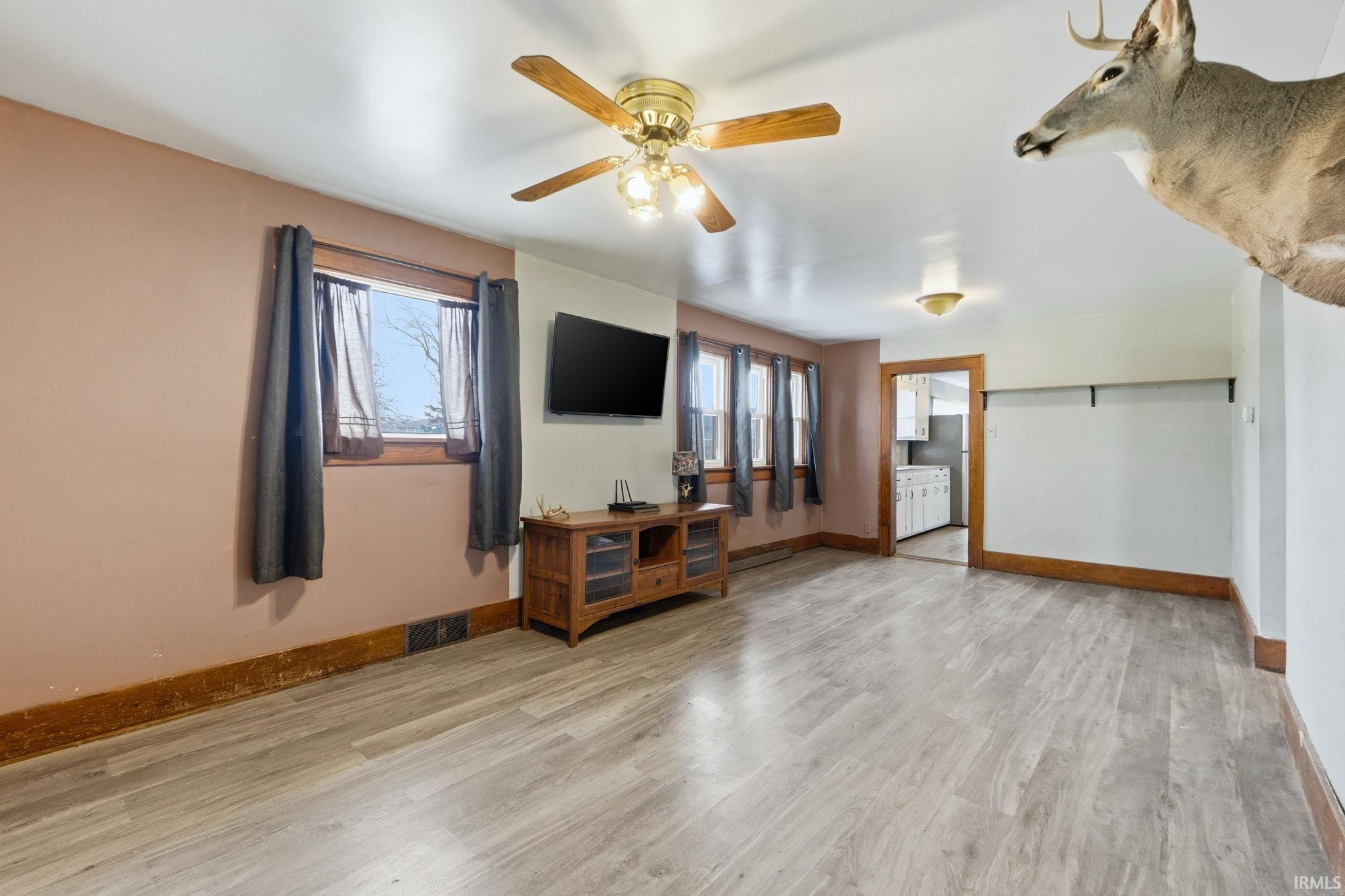 Living area featuring light wood finished floors, healthy amount of natural light, and a ceiling fan