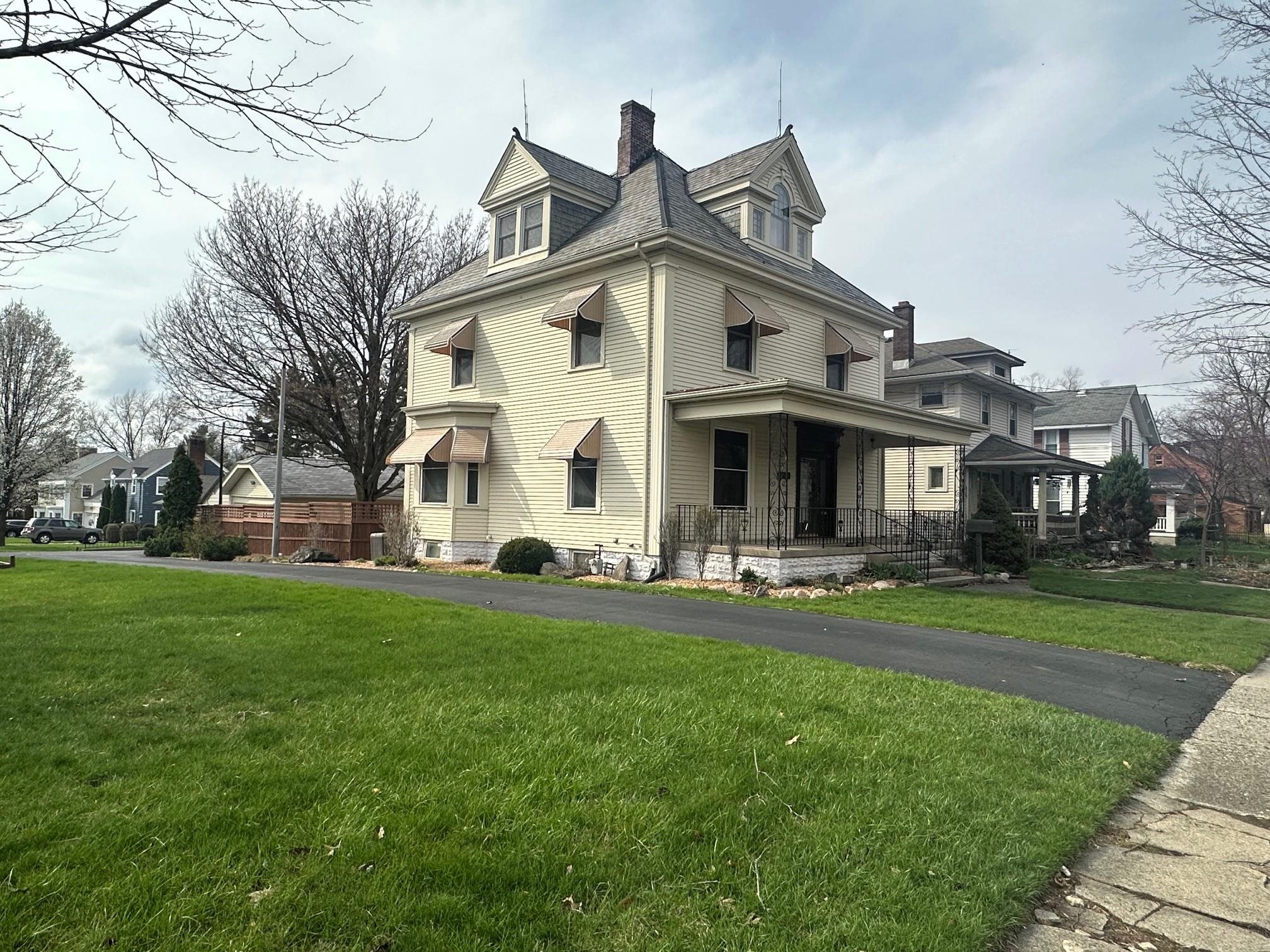 View of side of home with covered porch, a chimney, and a residential view
