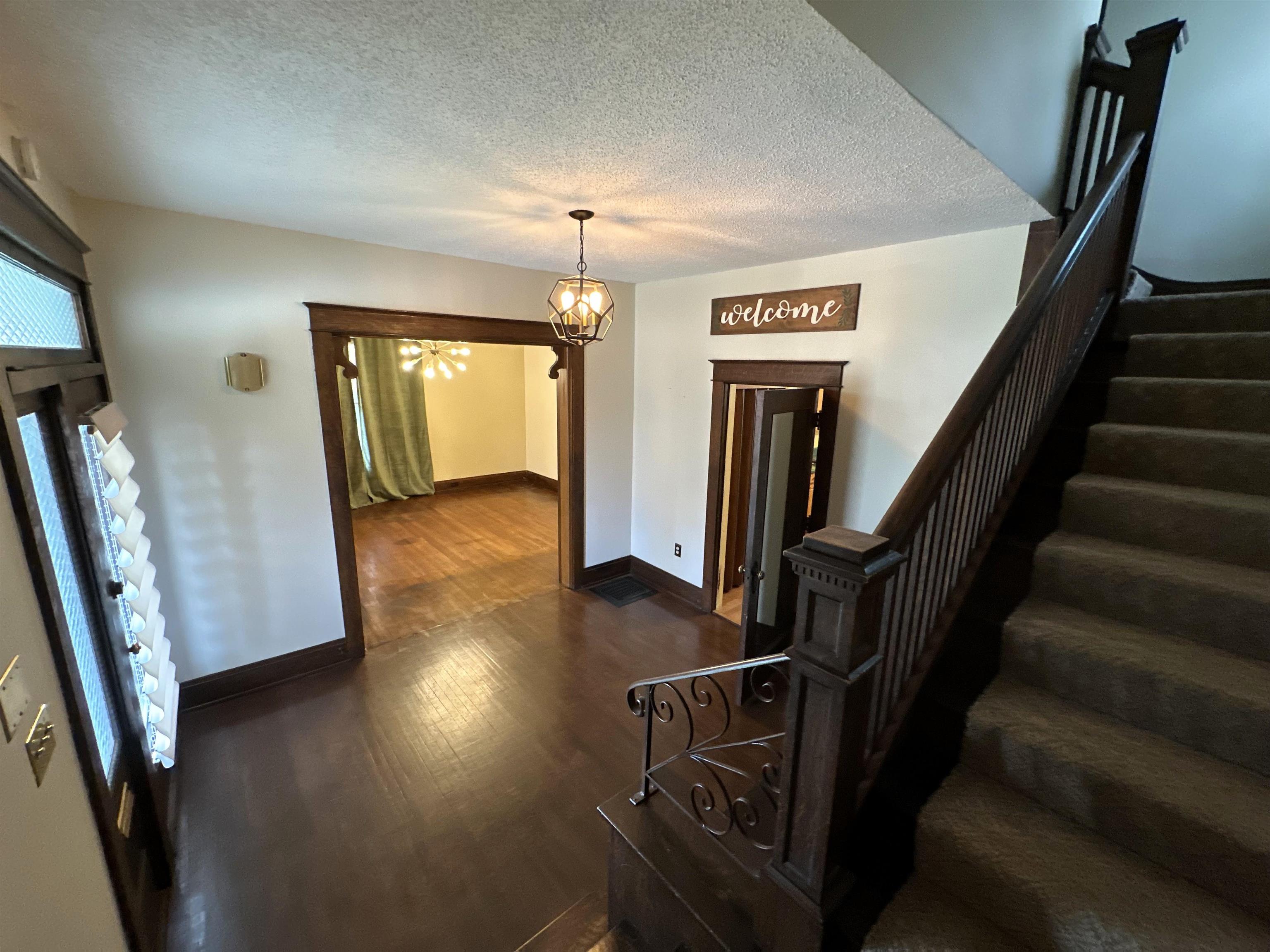 Entrance foyer featuring a chandelier, dark wood-type flooring, and a textured ceiling