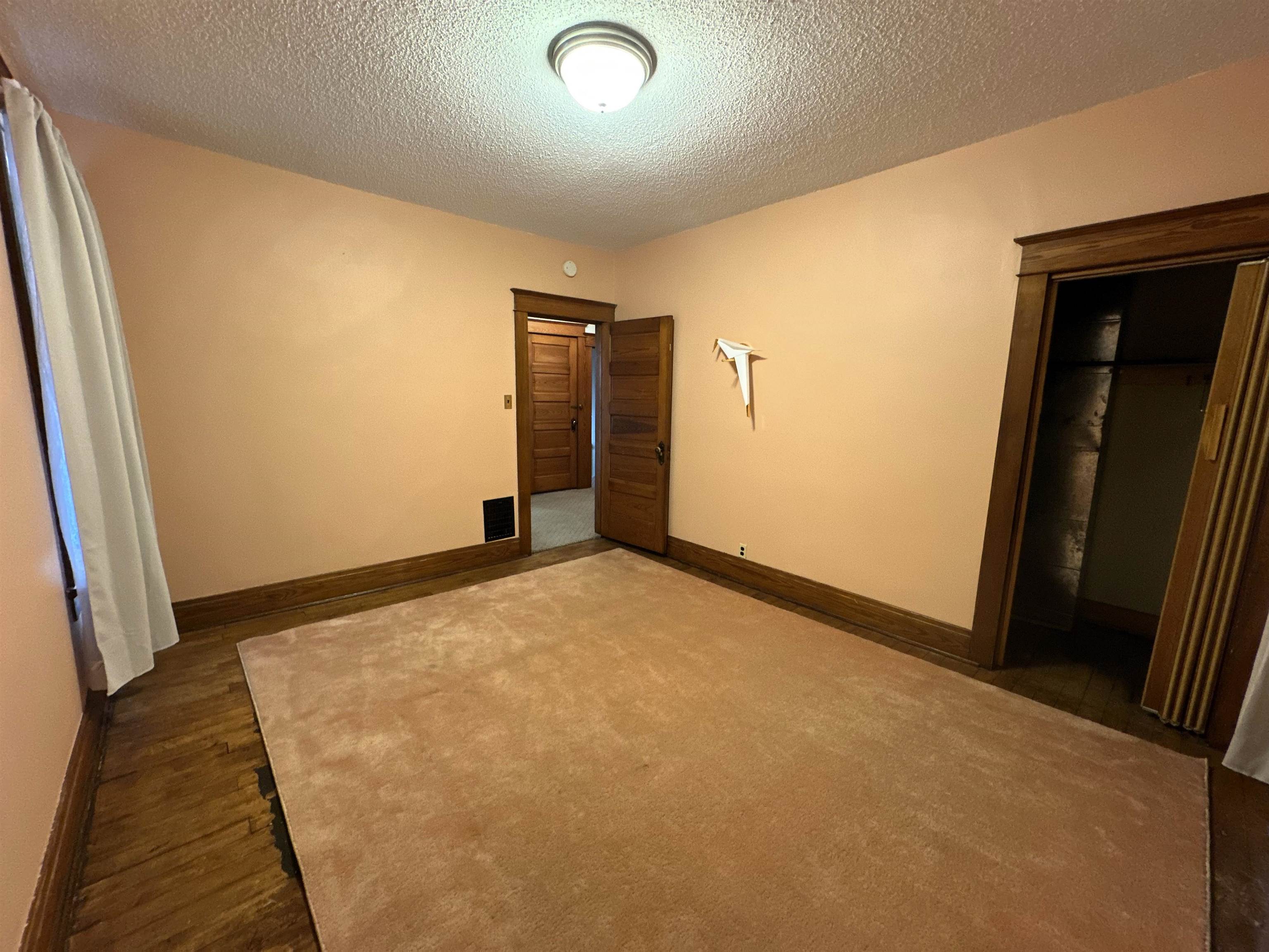 Unfurnished bedroom featuring a textured ceiling and dark wood-style flooring