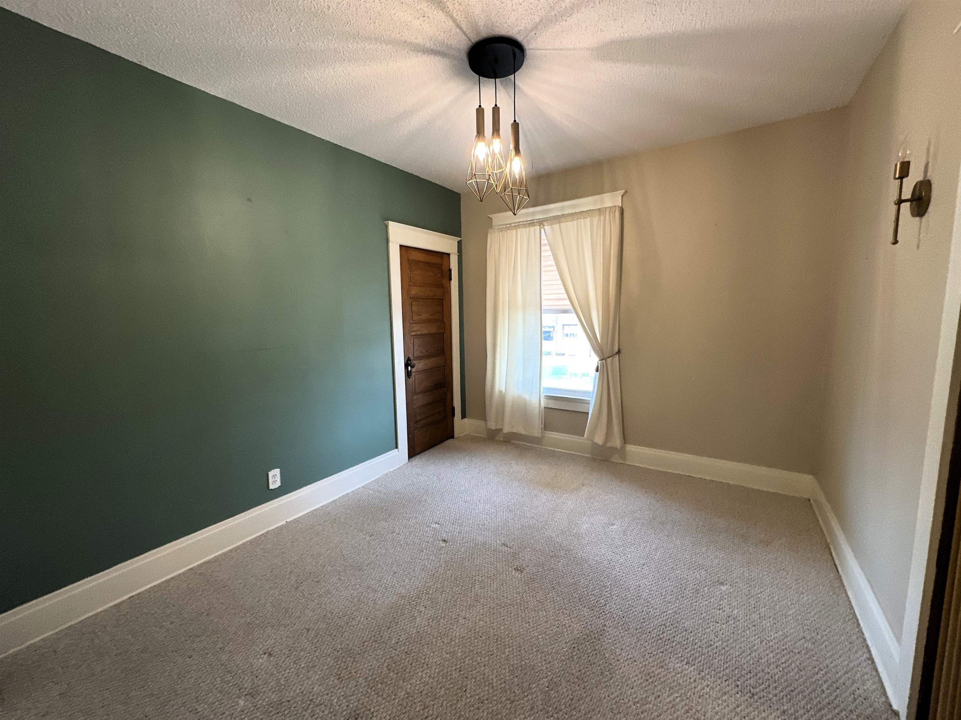 Spare room featuring light colored carpet, a textured ceiling, and hanging lights