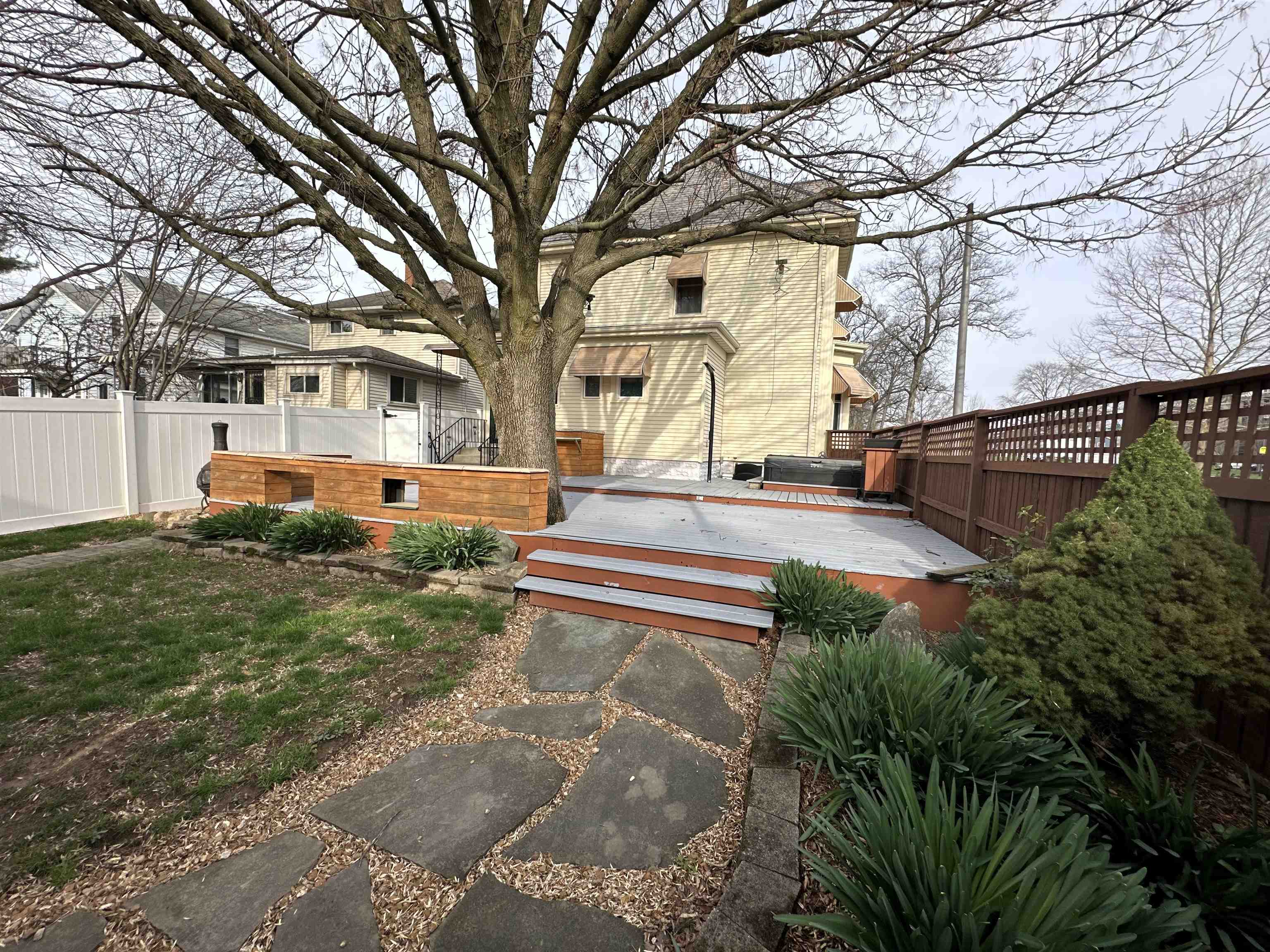 Back of property with a wooden deck and a hot tub