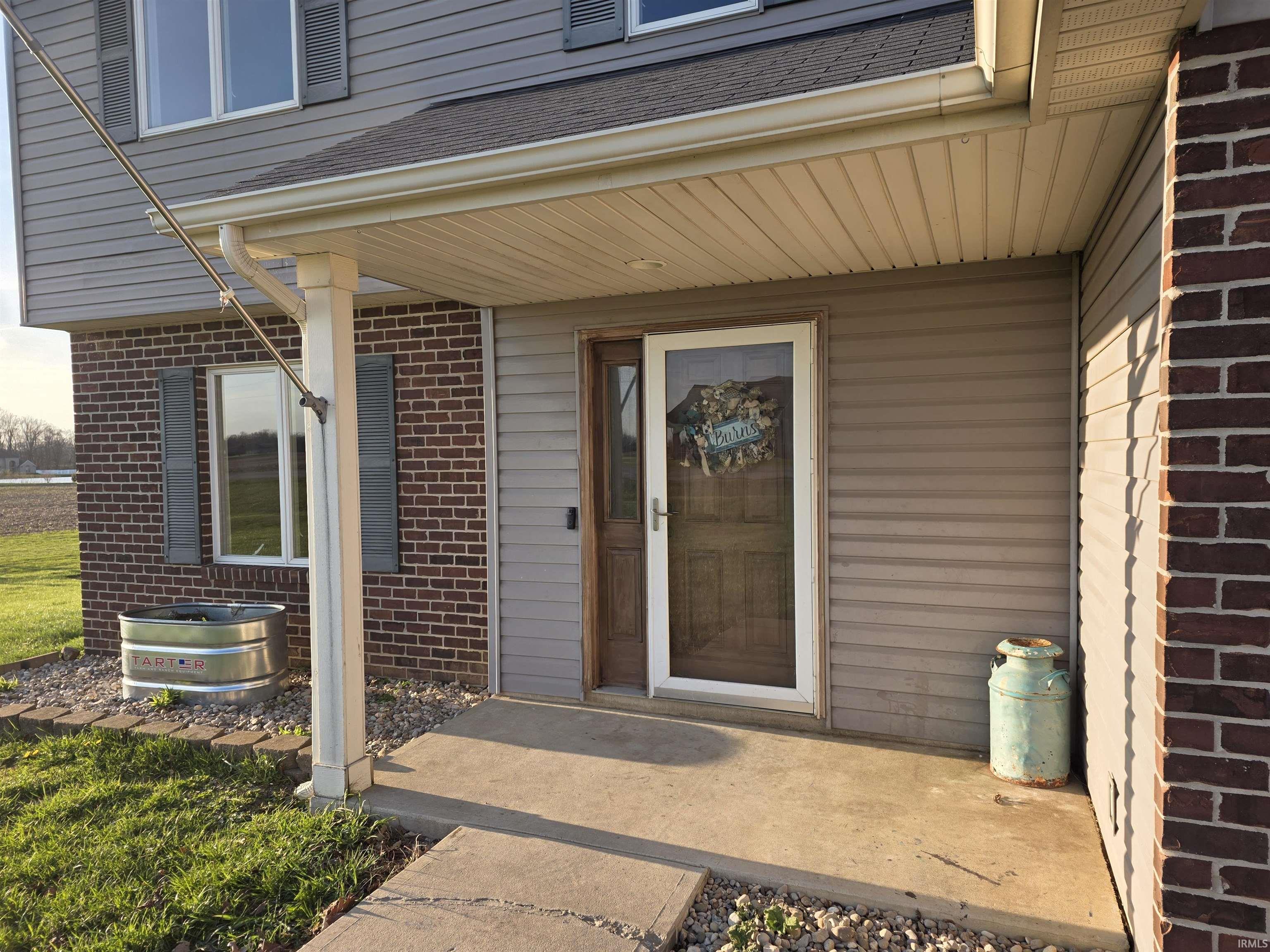 Property entrance featuring brick siding and roof with shingles