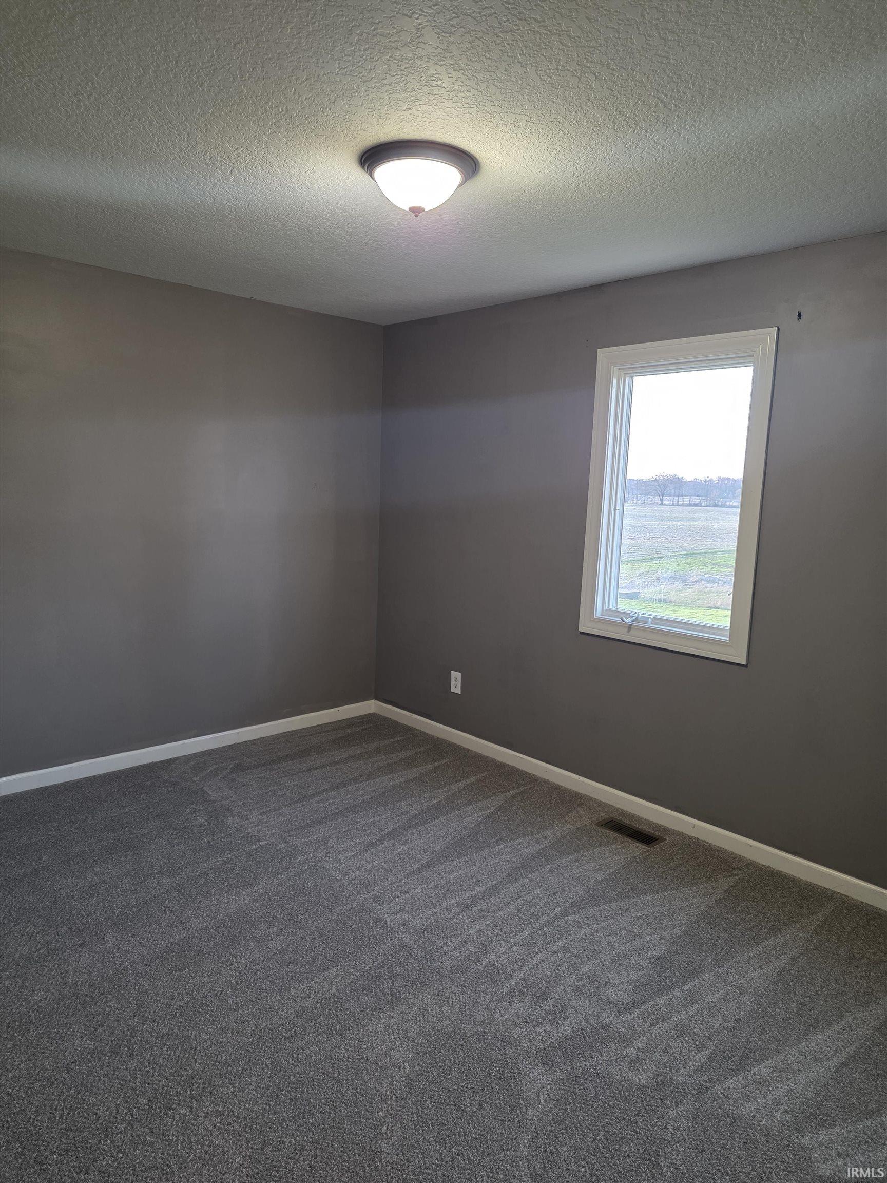 Spare room with a textured ceiling and dark carpet