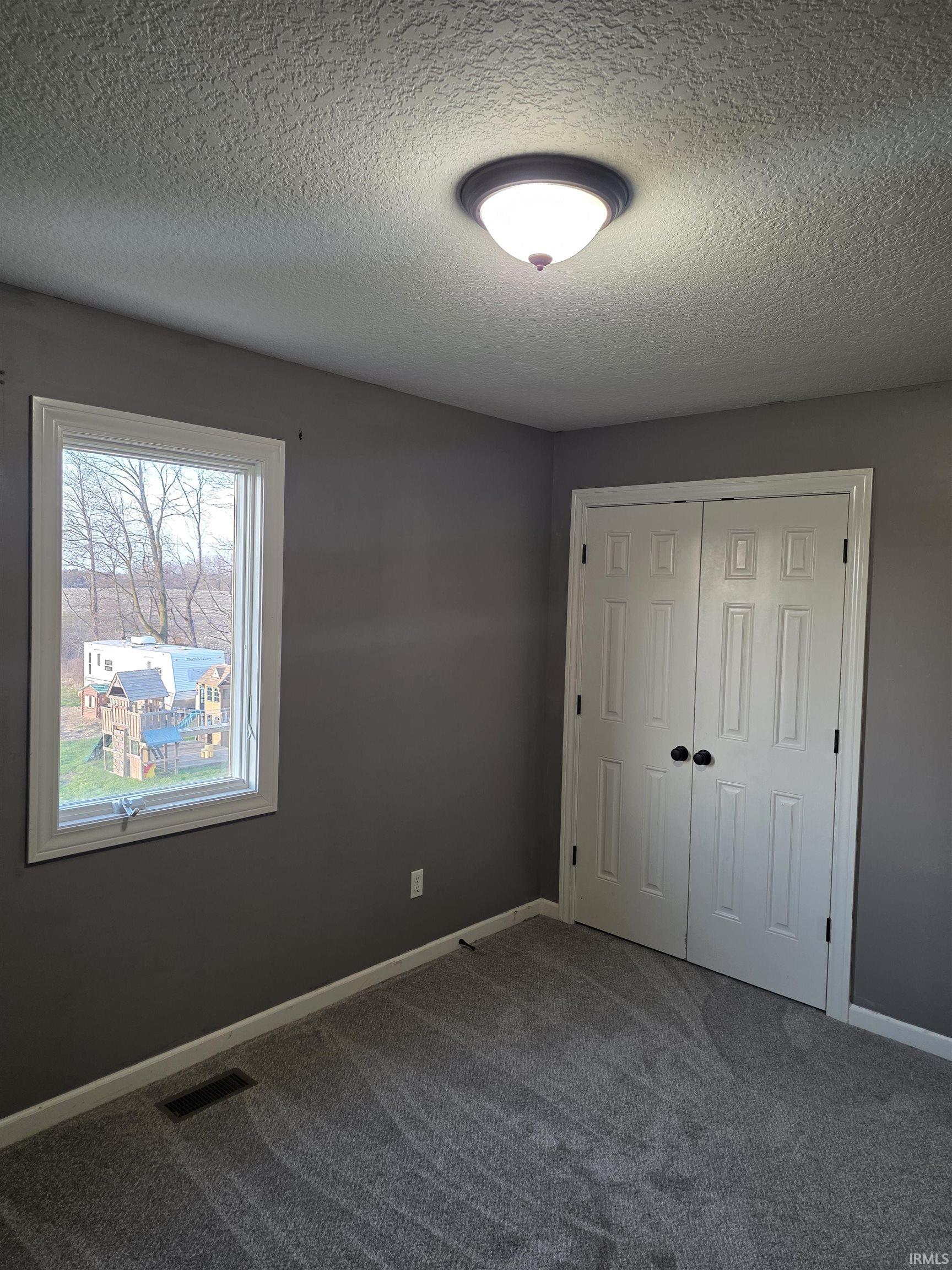 Unfurnished bedroom with a textured ceiling, a closet, and carpet flooring